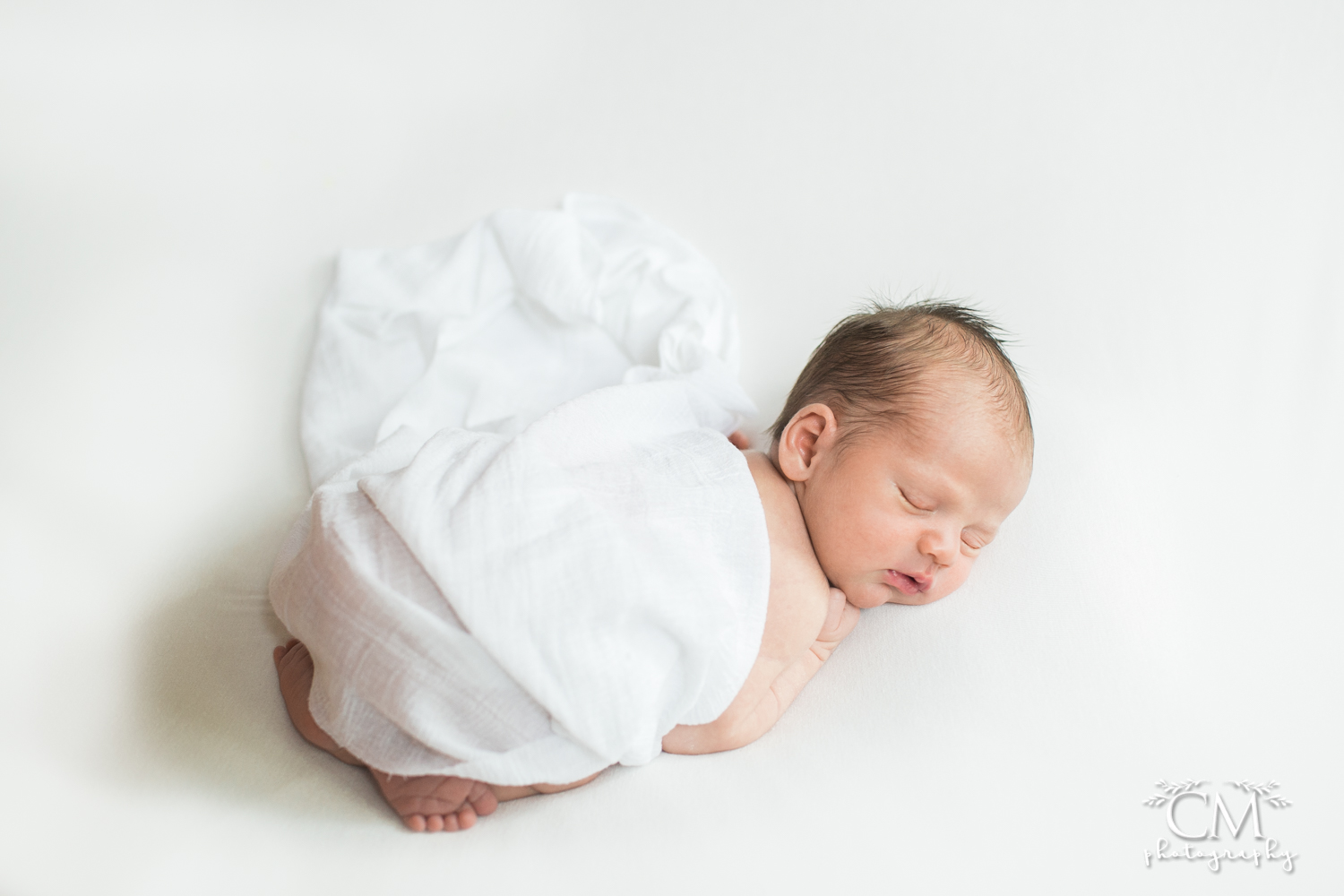 sleepy newborn draped in white fabric 