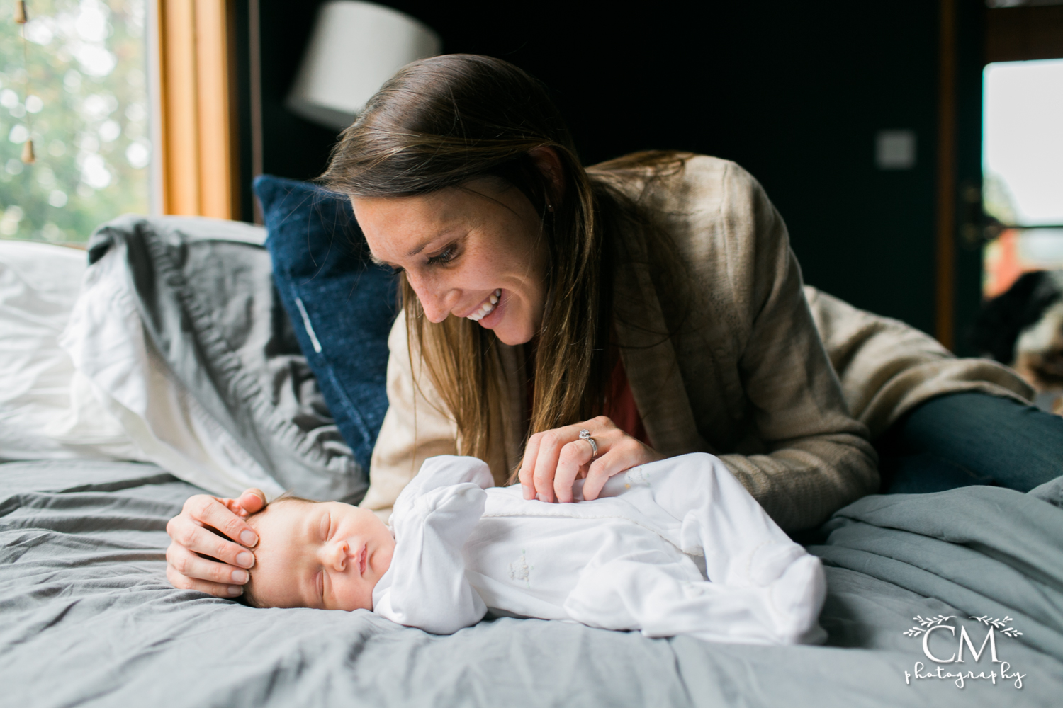 mom in bed smiling with newborn baby