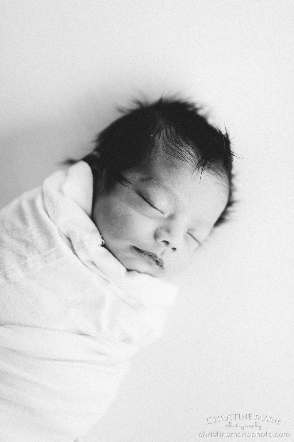 wrapped up newborn baby in grainy black and white