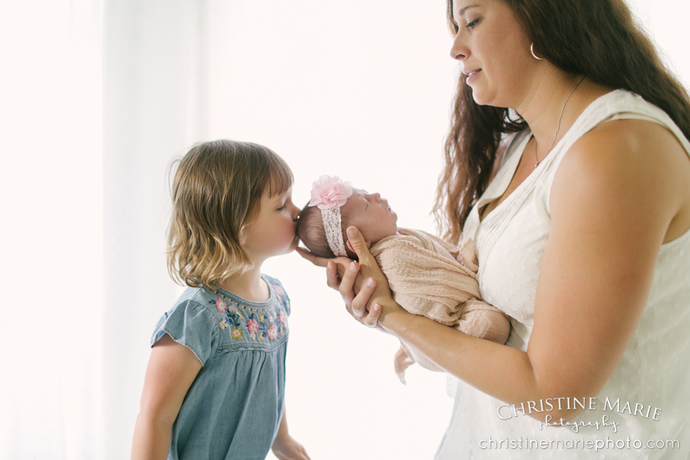 toddler big sister kissing baby sister 