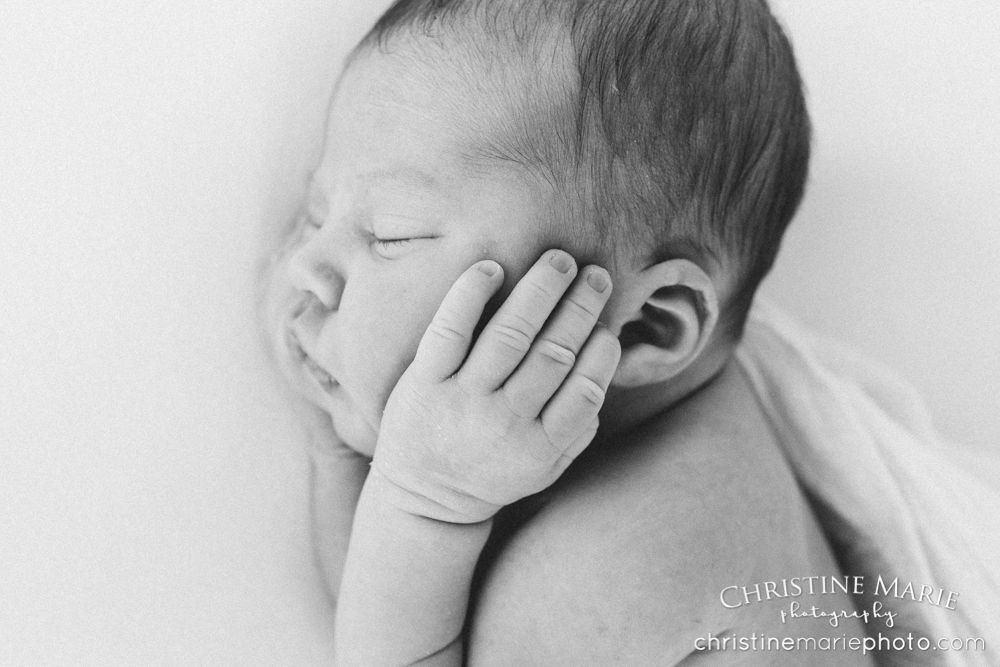 sleeping newborn hands on cheeks 