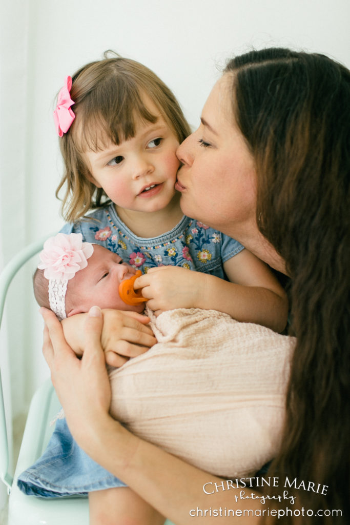 mama kissing and holding her little girls 