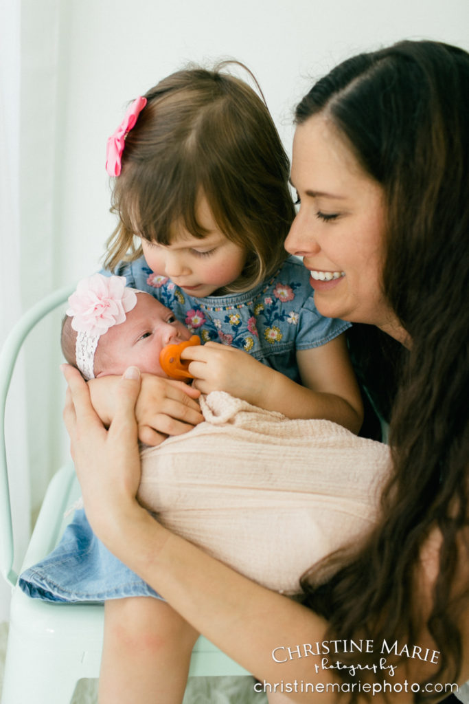 mother admiring her two little children and newborn 