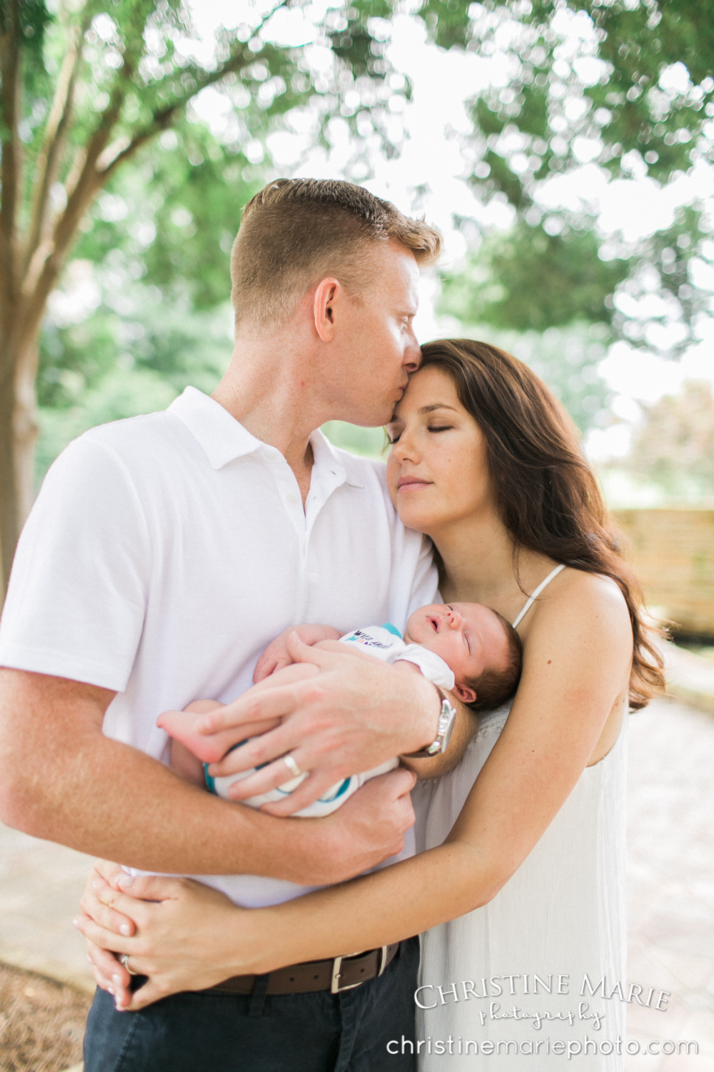 dad kissing mom holding newborn baby 