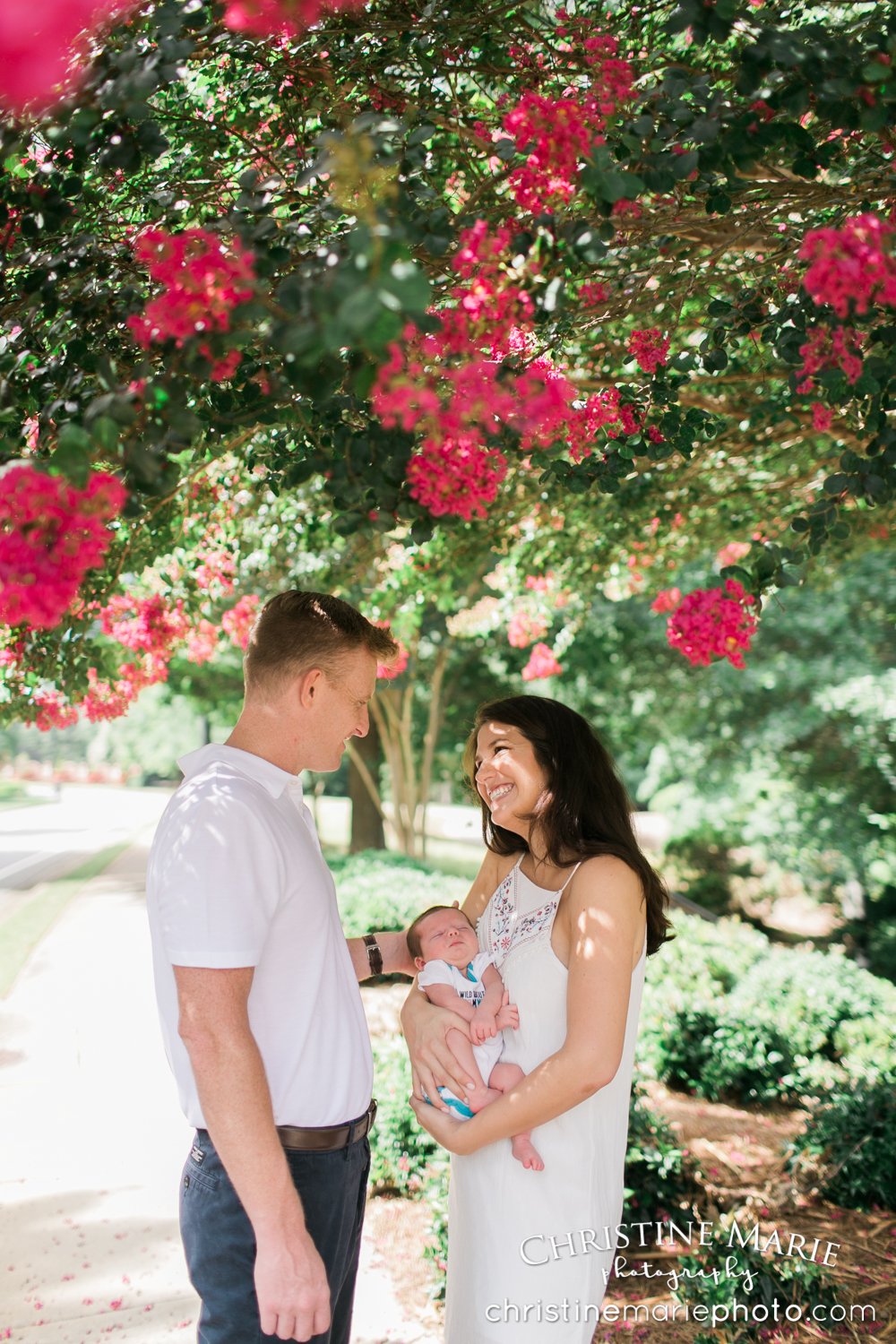 happy couple with their new baby under flowering pink tree 