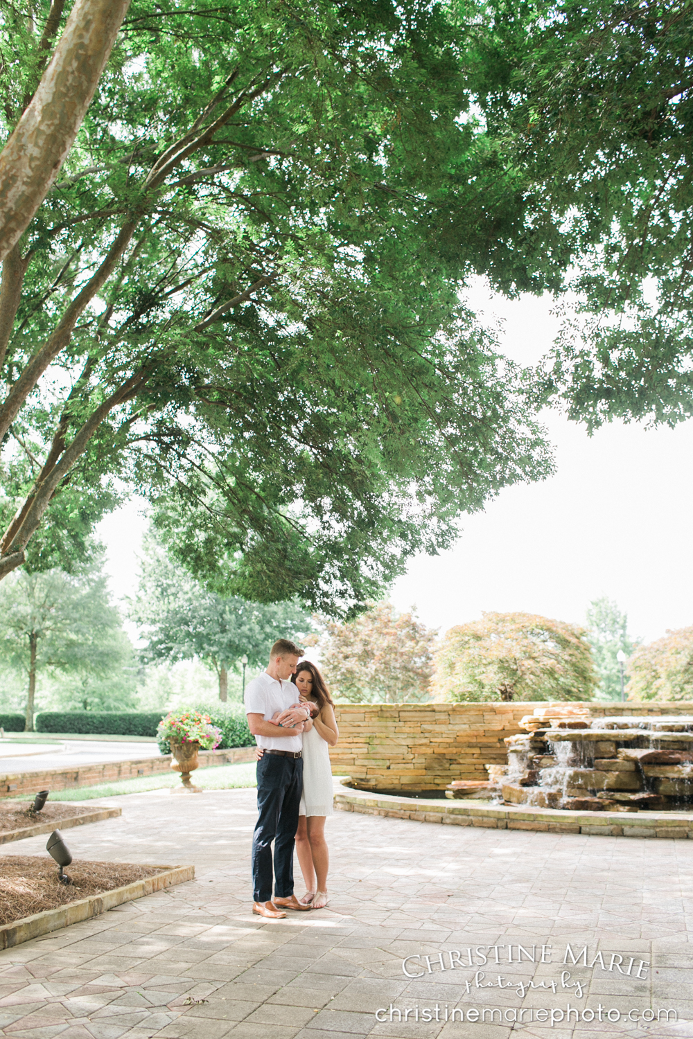 new parents admiring new baby under a tree