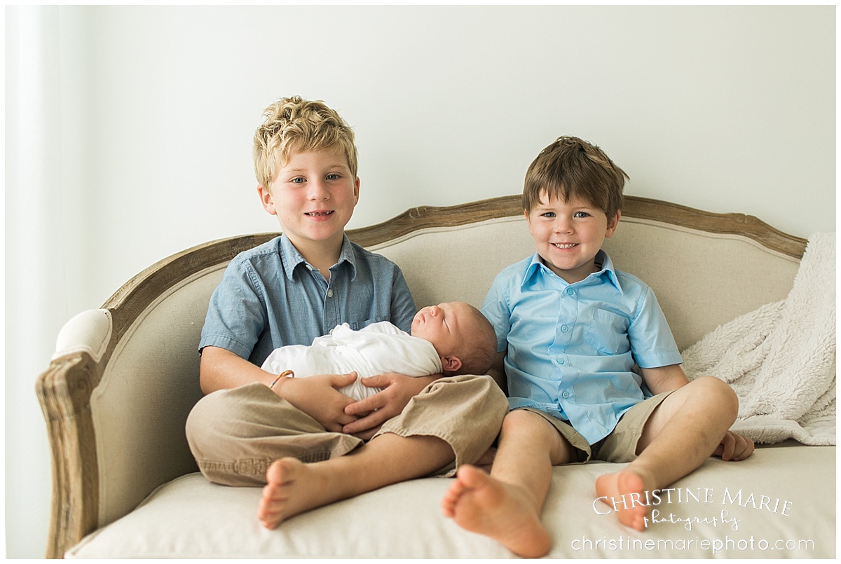 big brothers holding newborn baby on ballard designs couch