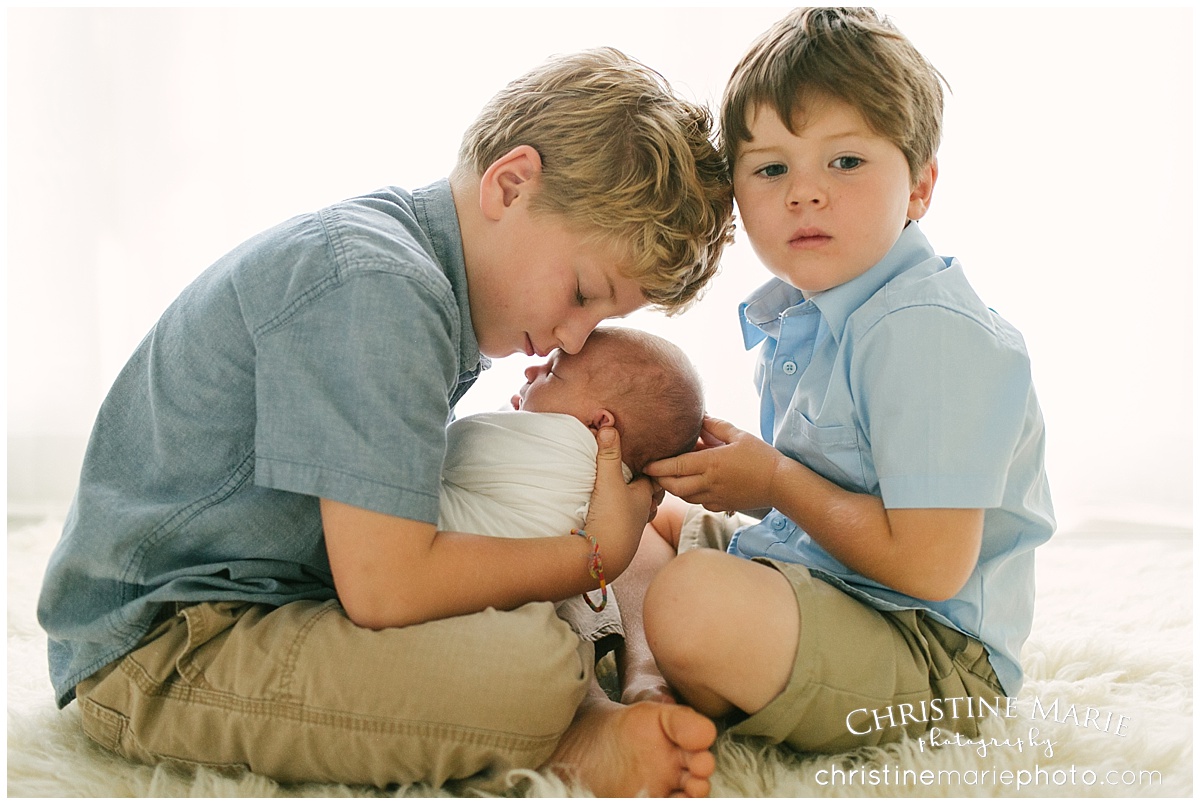 big brothers holding newborn baby