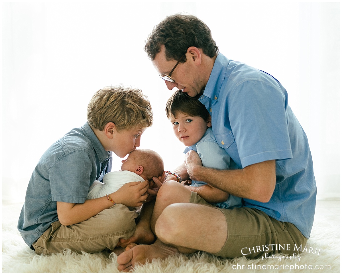 dad sitting with his 3 sons and newborn