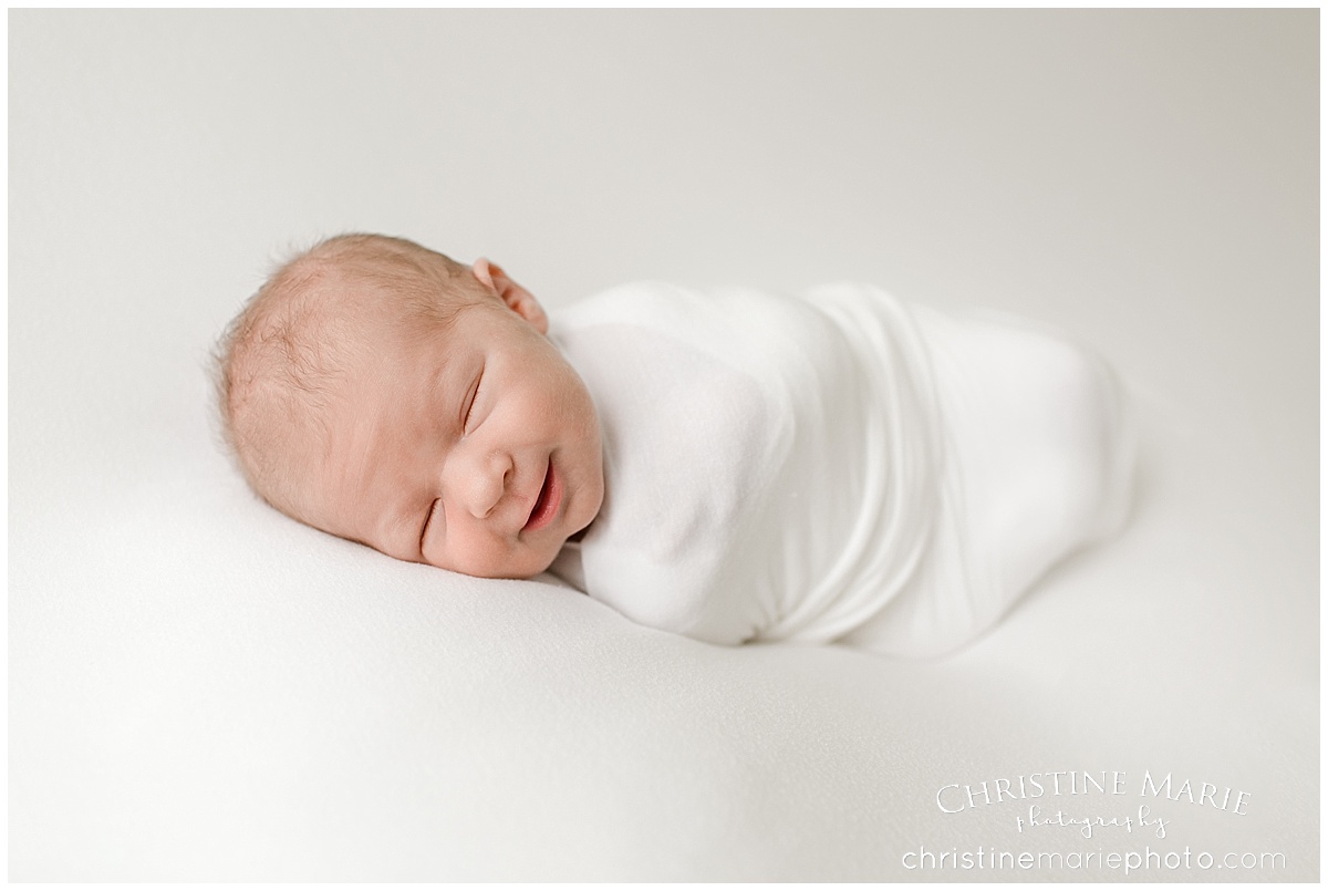smiling newborn baby wrapped up