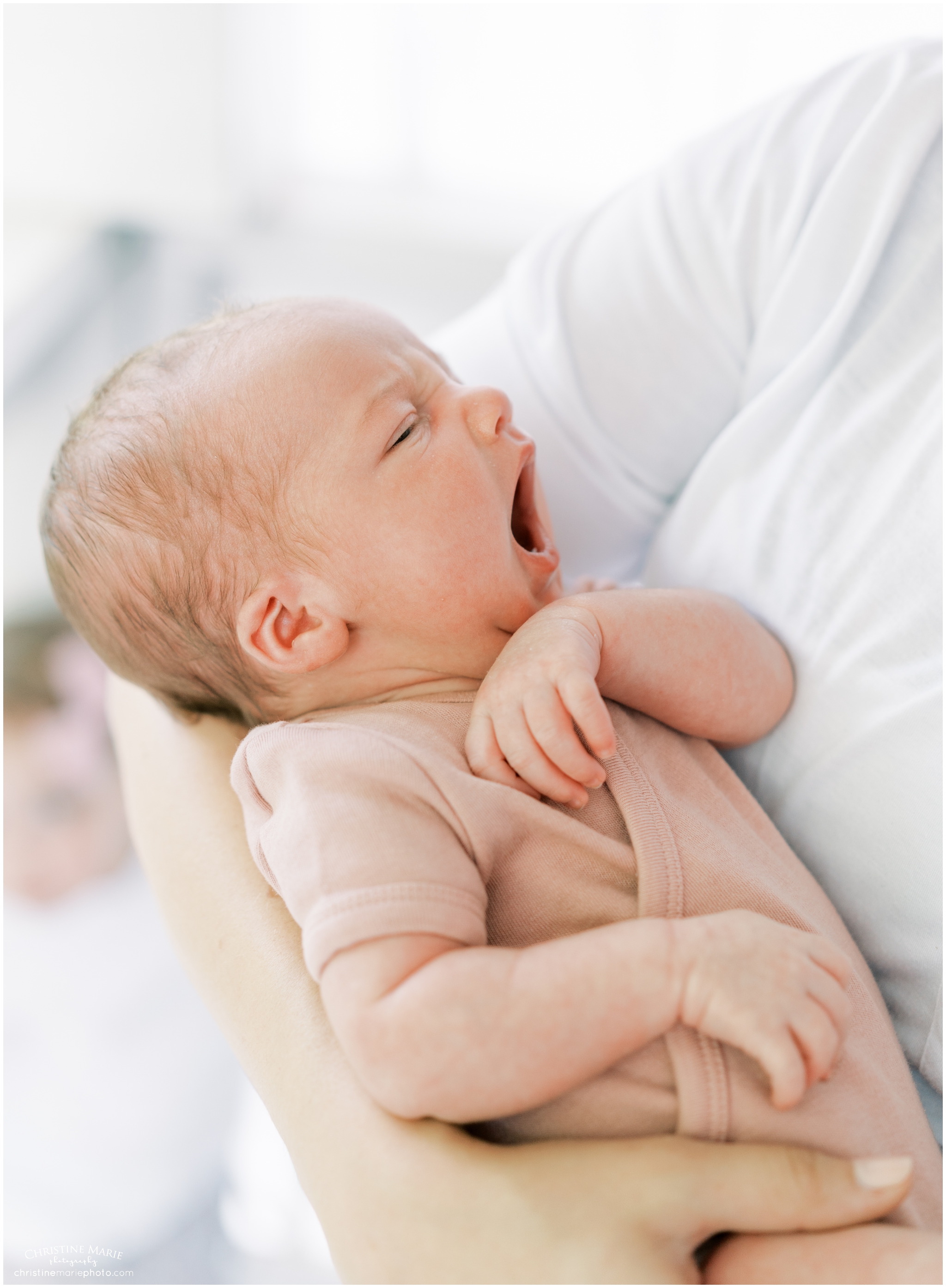 yawning baby girl in mothers arm during newborn session in Atlanta
