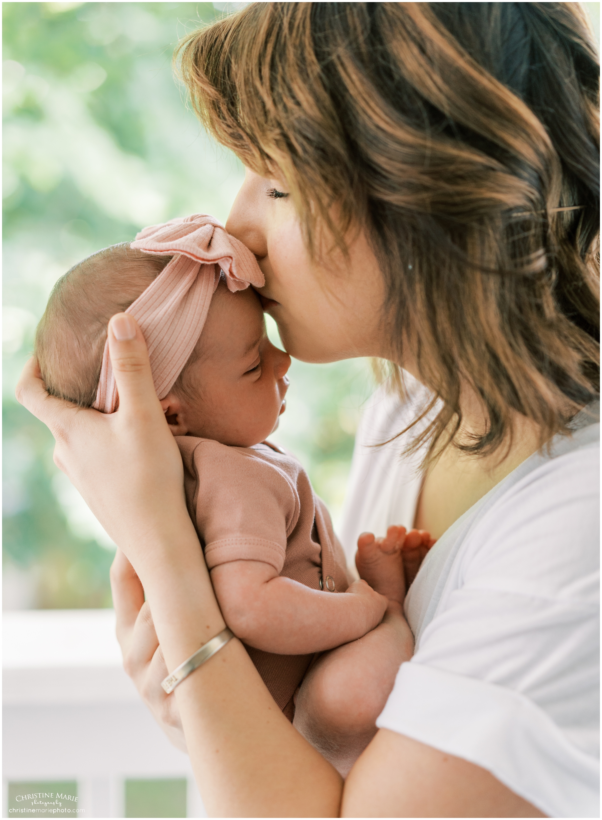 mom kissing new baby girl on back porch