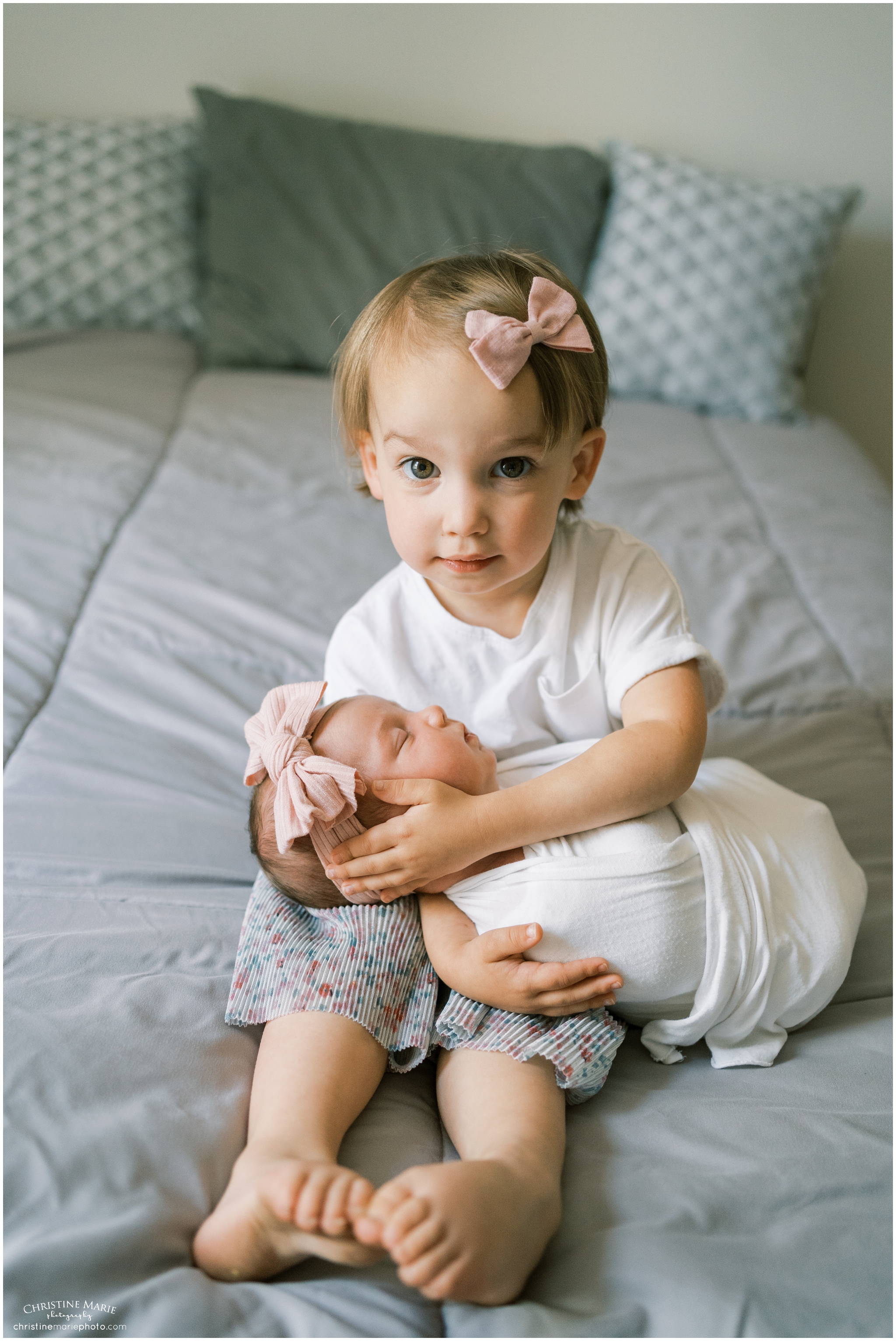 toddler little girl holding new baby sister in atlanta lifestyle newborn session