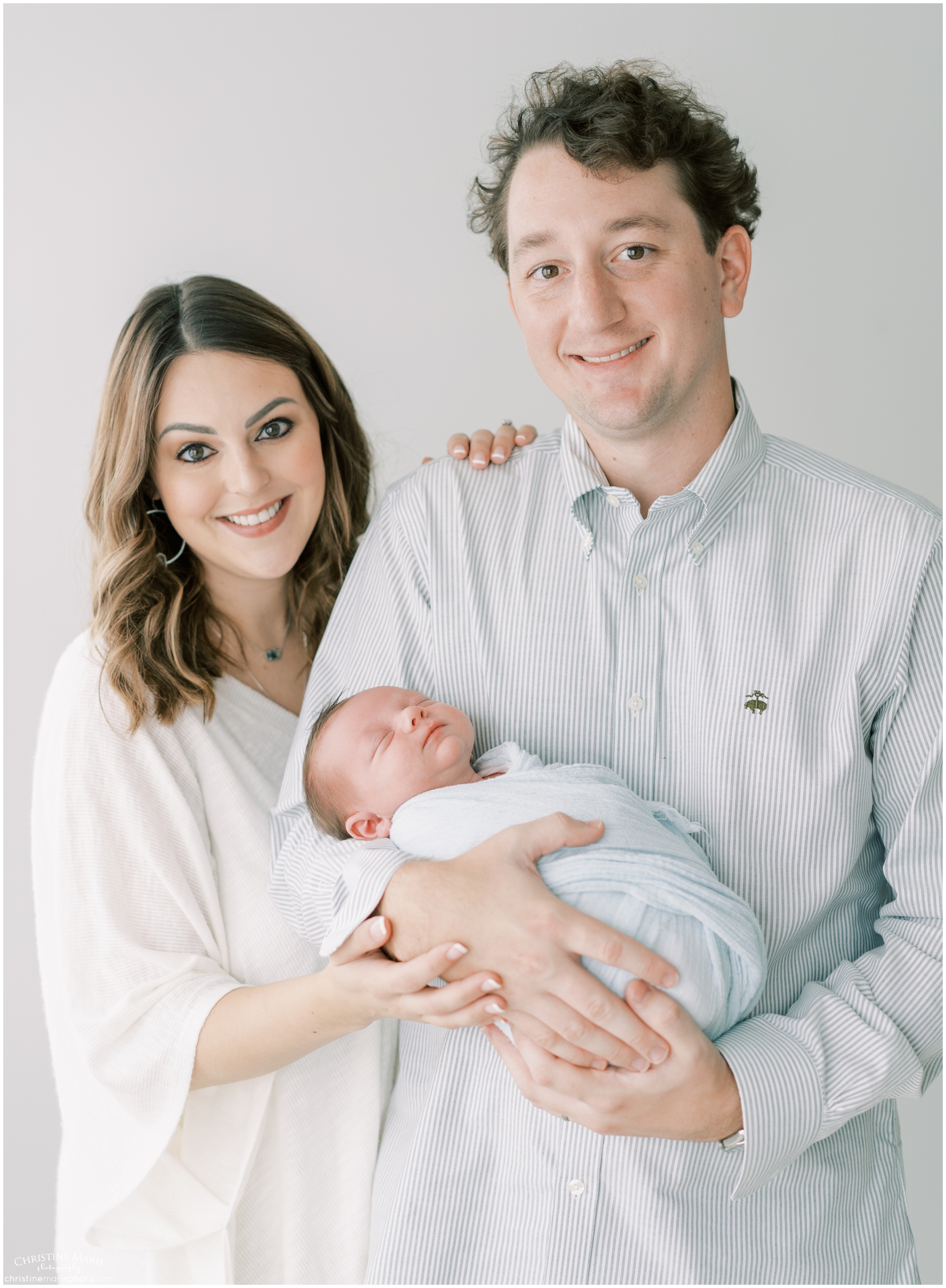 new parents smiling big ad hold baby boy in cumming photography studio