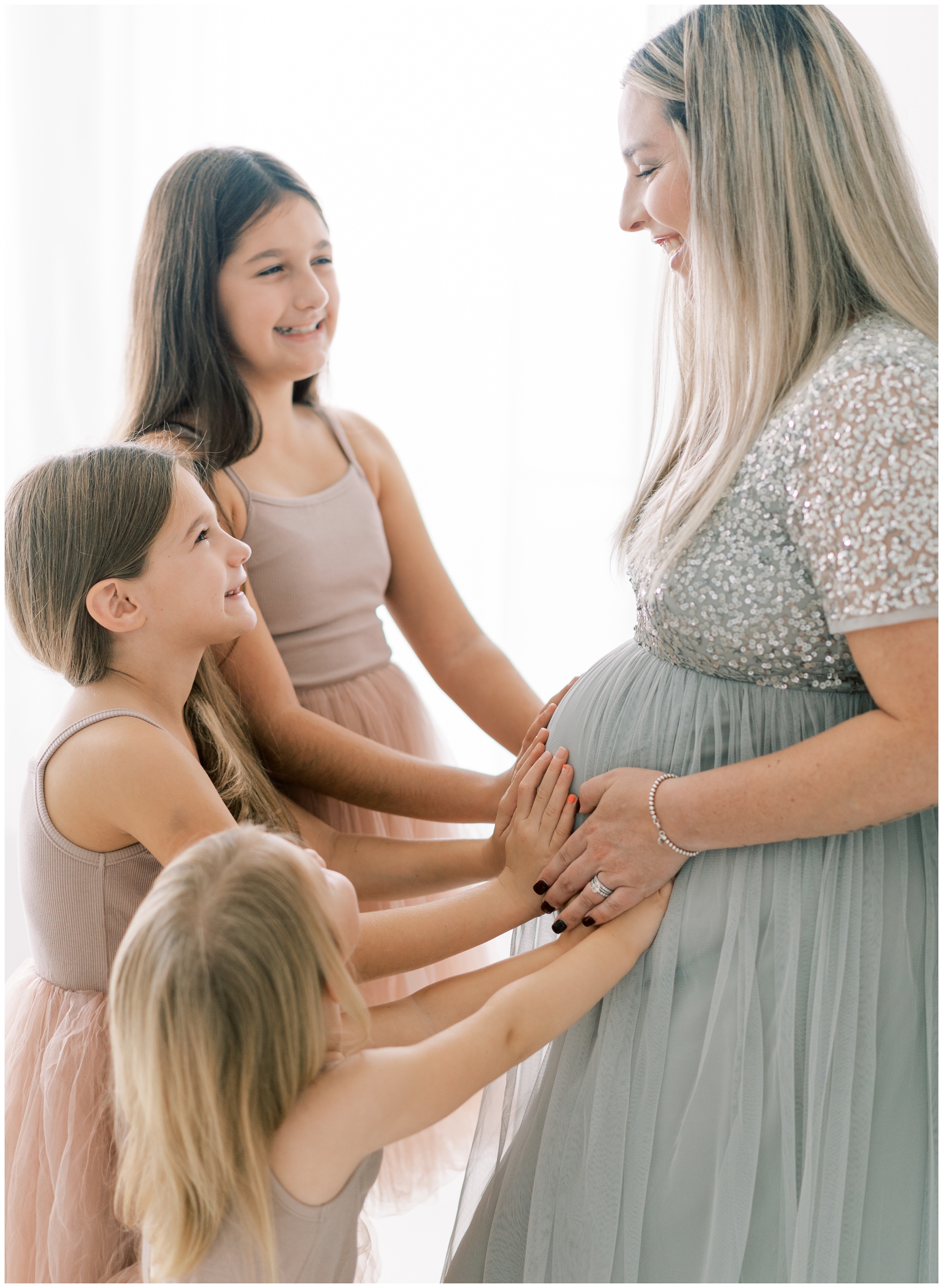 little girls with hands on mommy's pregnant belly