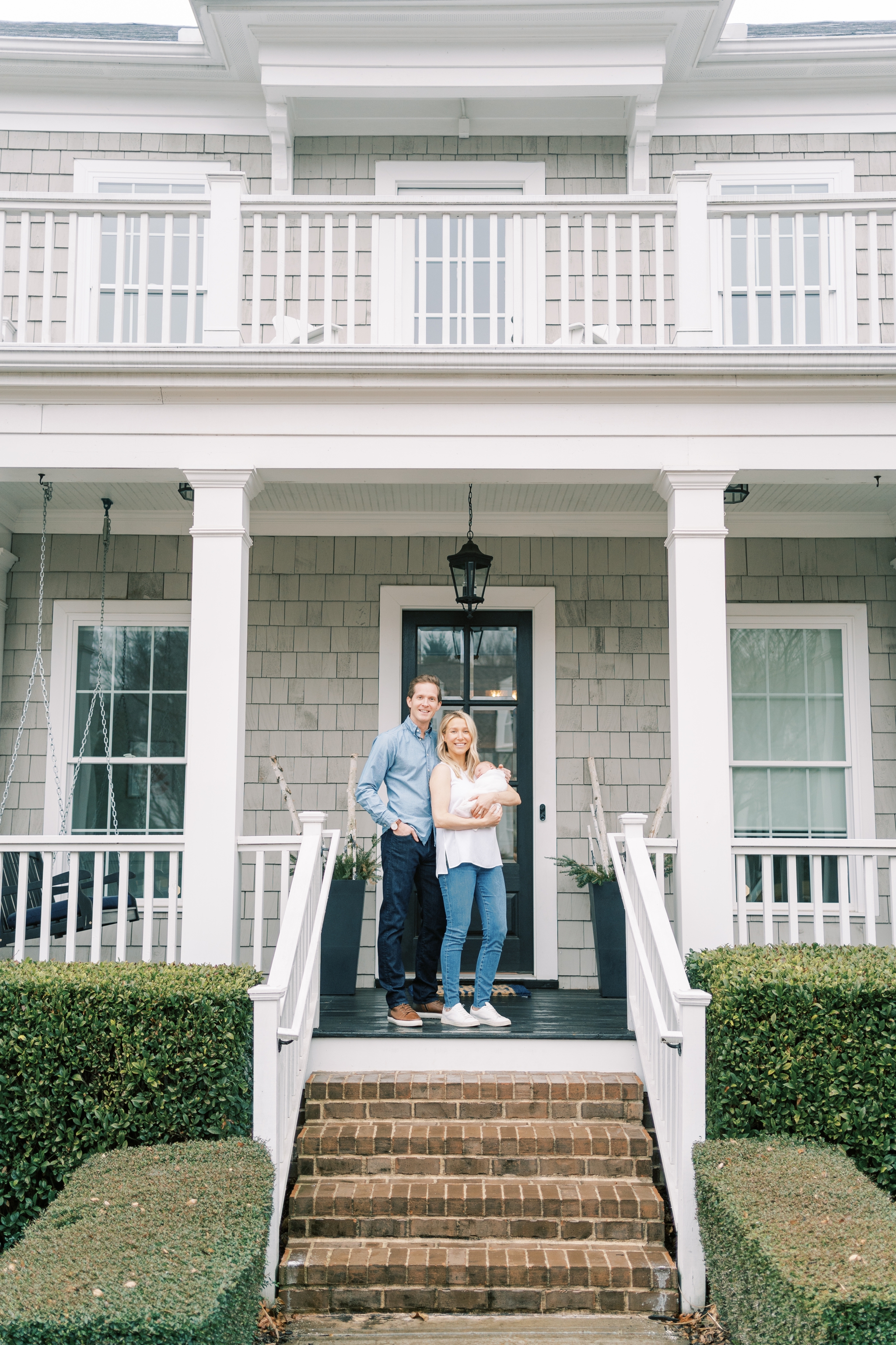 parents holding new baby in front of new house in Roswell GA