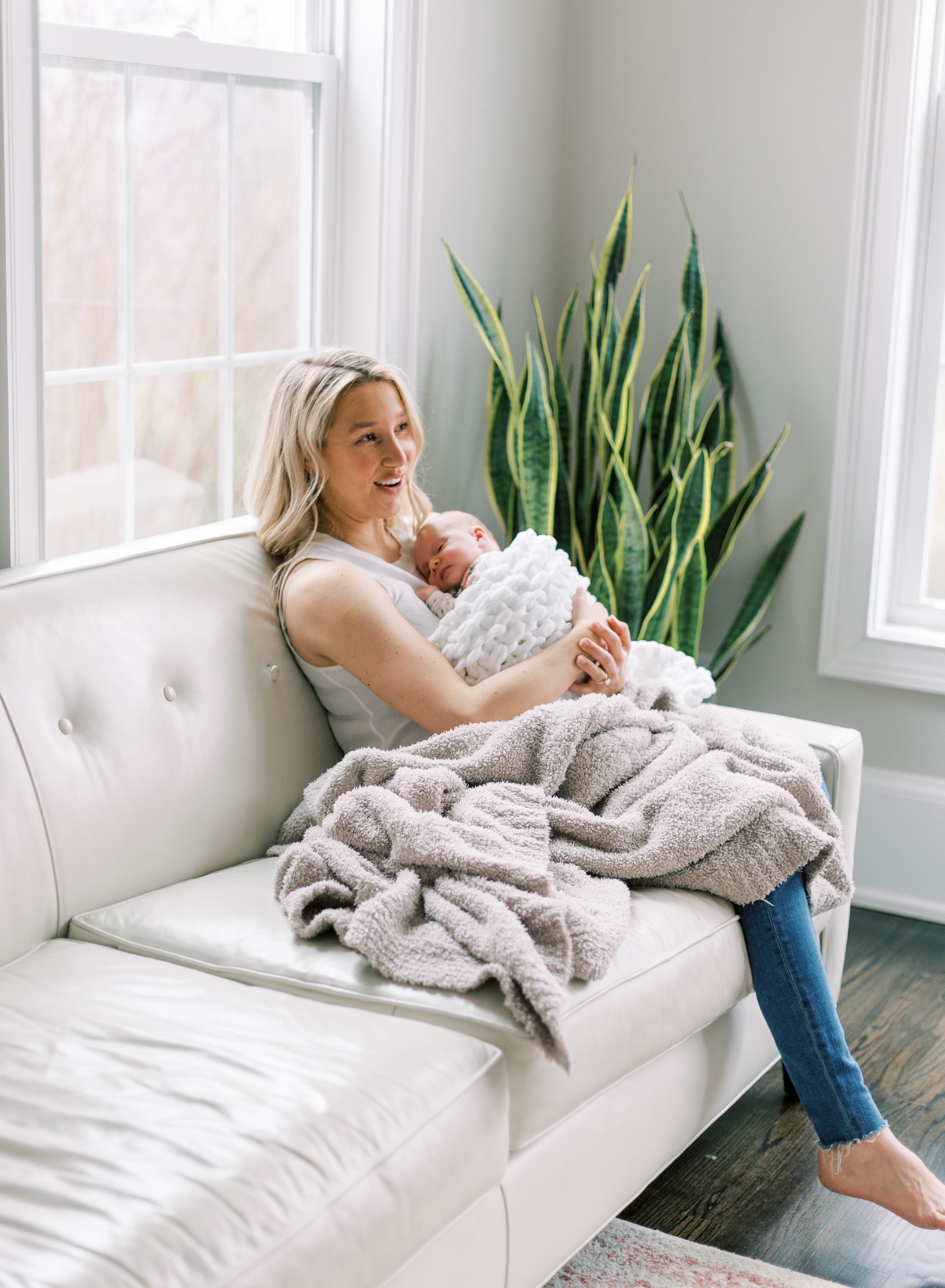 mom lounging on couch with newborn baby girl in lifestyle newborn session