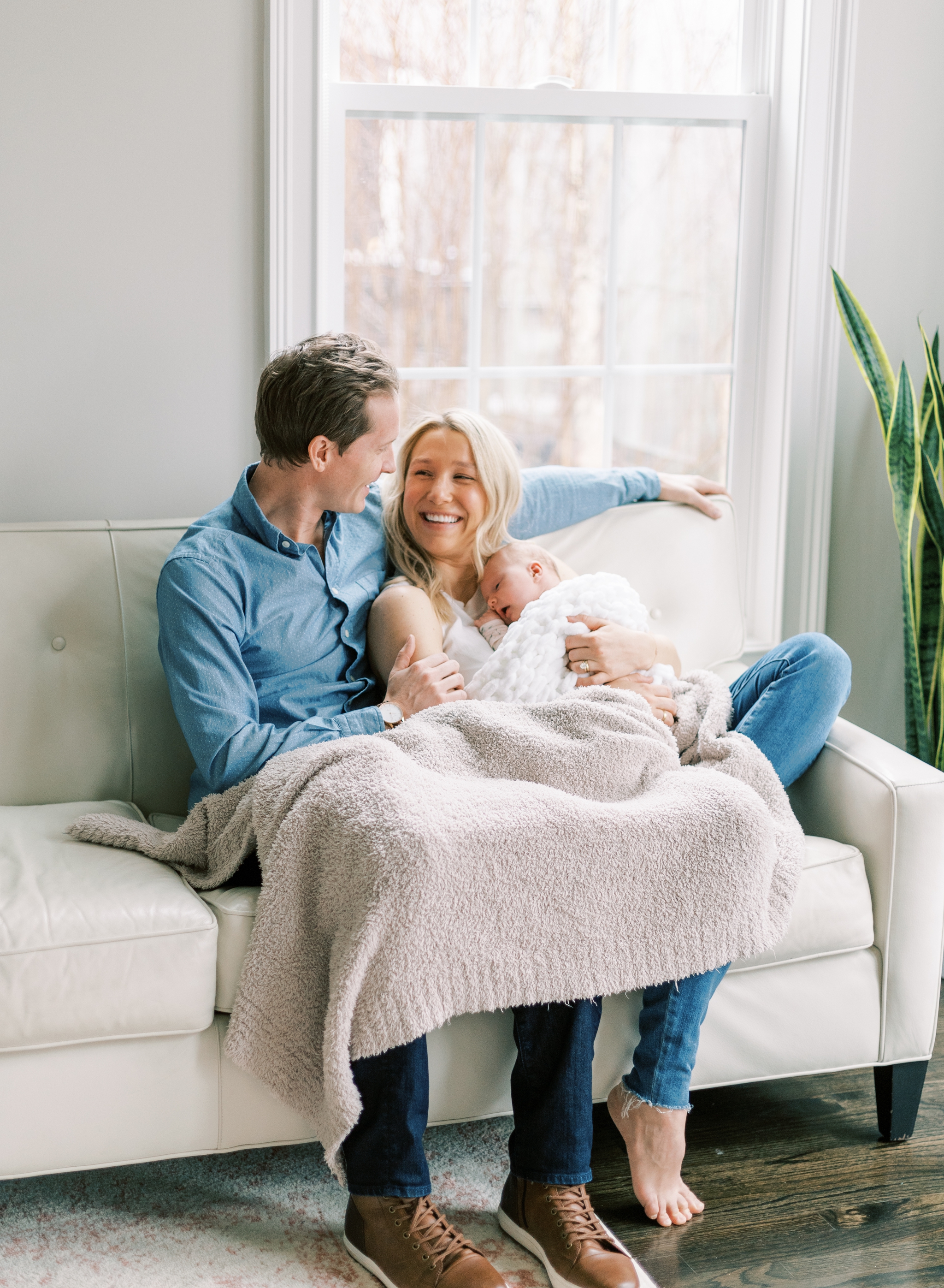 happy family of three lounging on couch with new baby in Roswell, GA