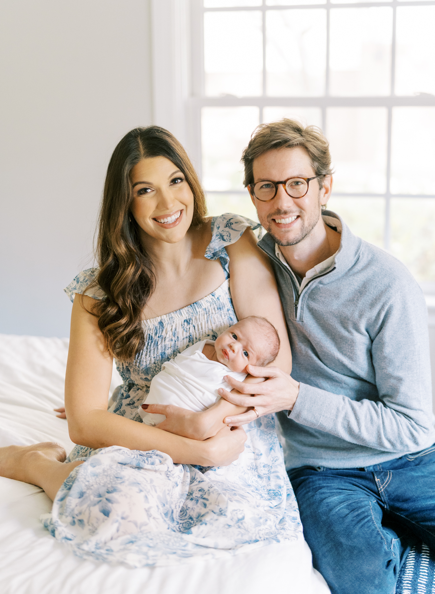 Happy new parents holding baby boy in sun drenched room