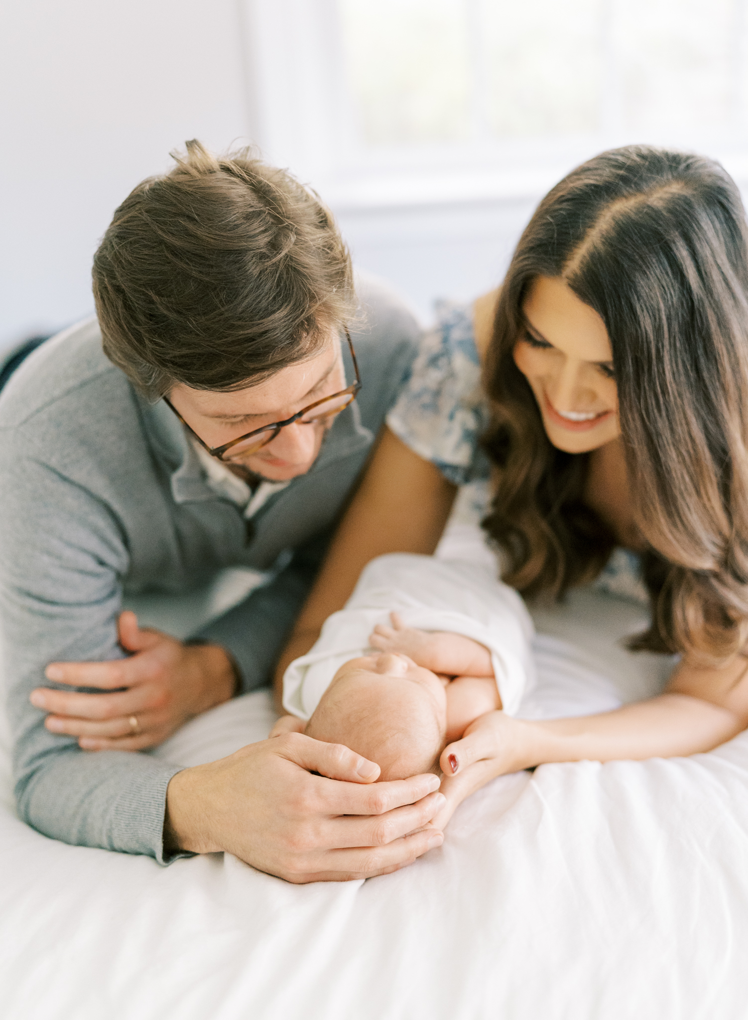 A mom and dad holding their newborn son in their bed