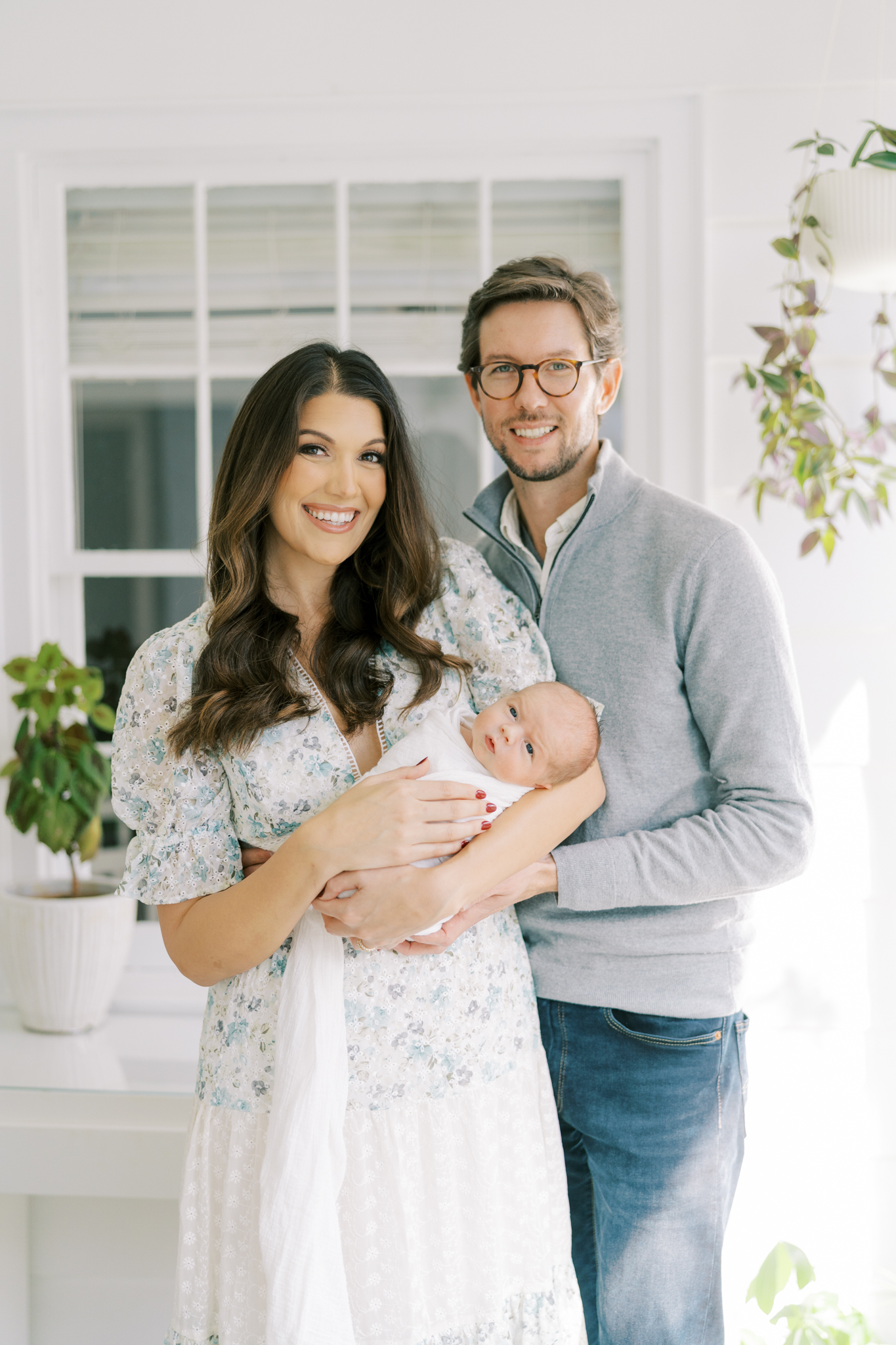 Happy new family of three smiling for newborn photos in Atlanta home. 