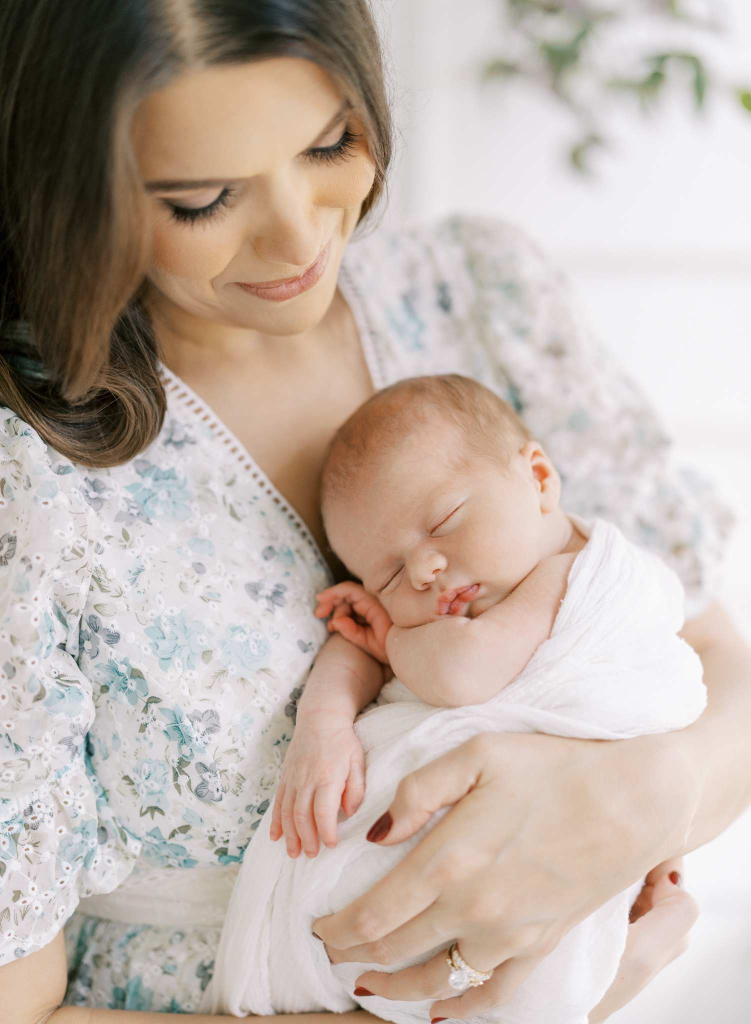 New mother snuggling her baby boy on her chest during lifestyle newborn photoshoot. 