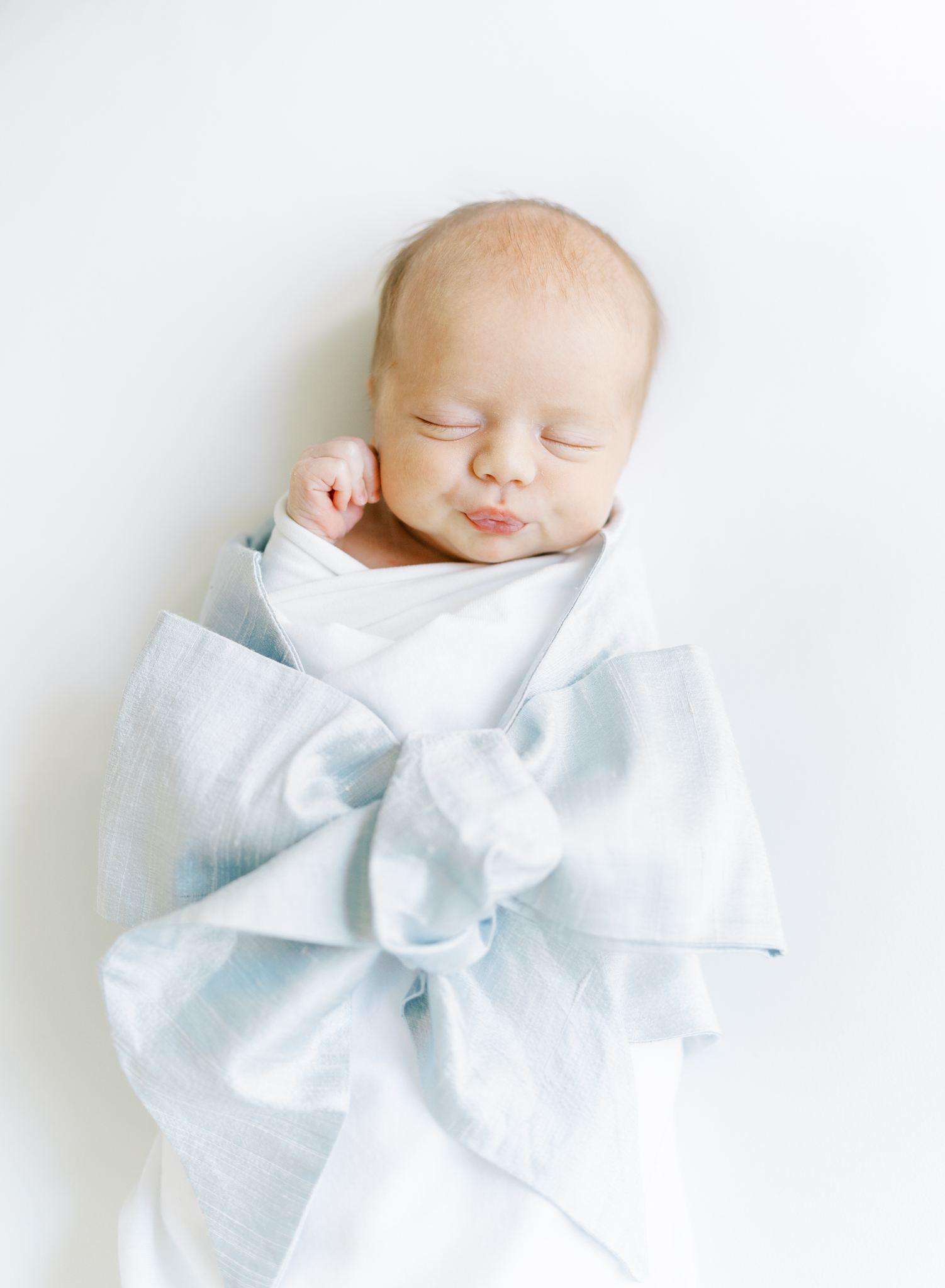 Precious baby boy pickering his lips in the Beaufort Bonnet Bow Swaddle 