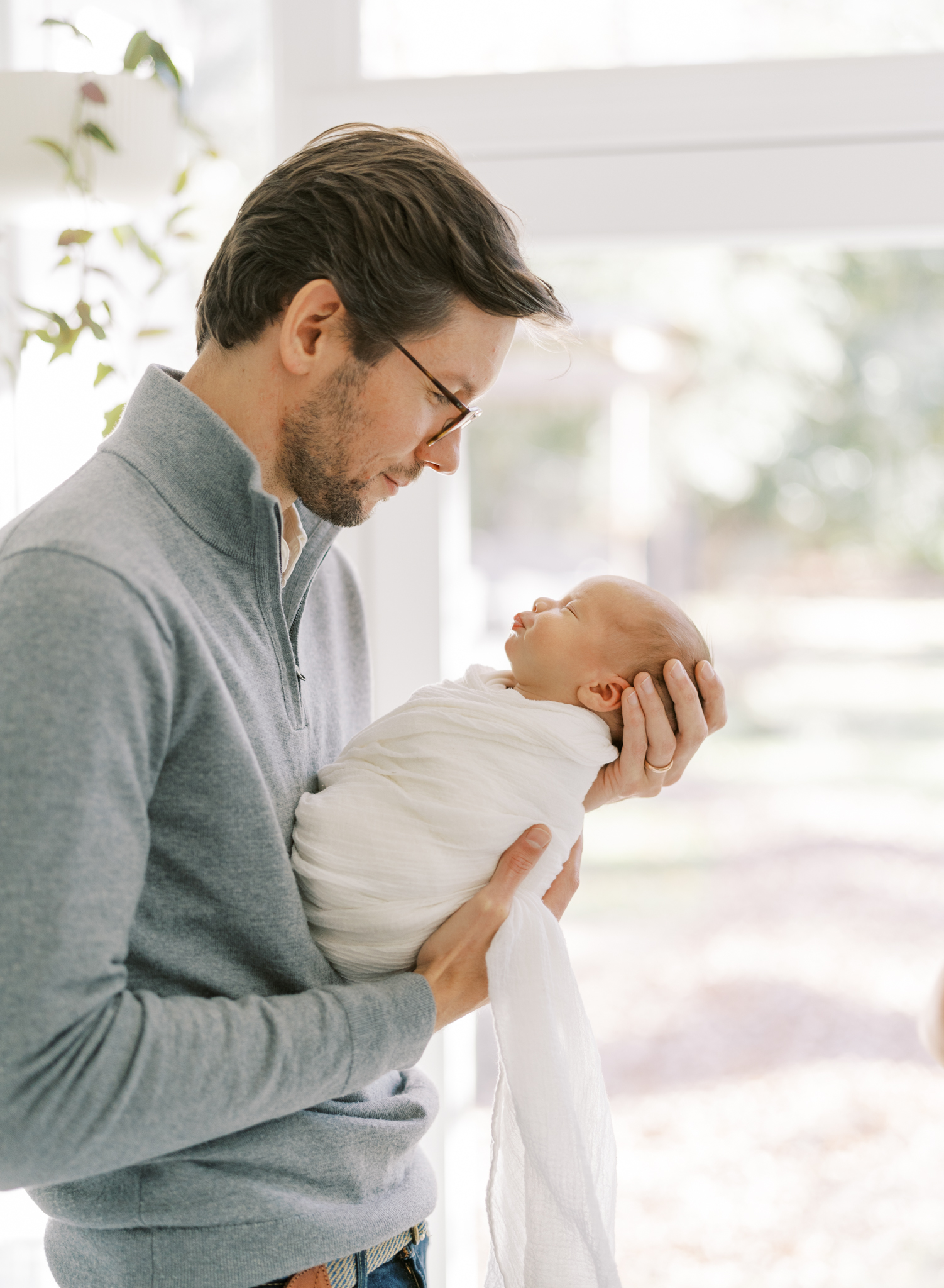 Adoring father holding his newborn baby boy in the sunroom of his Atlanta home. 