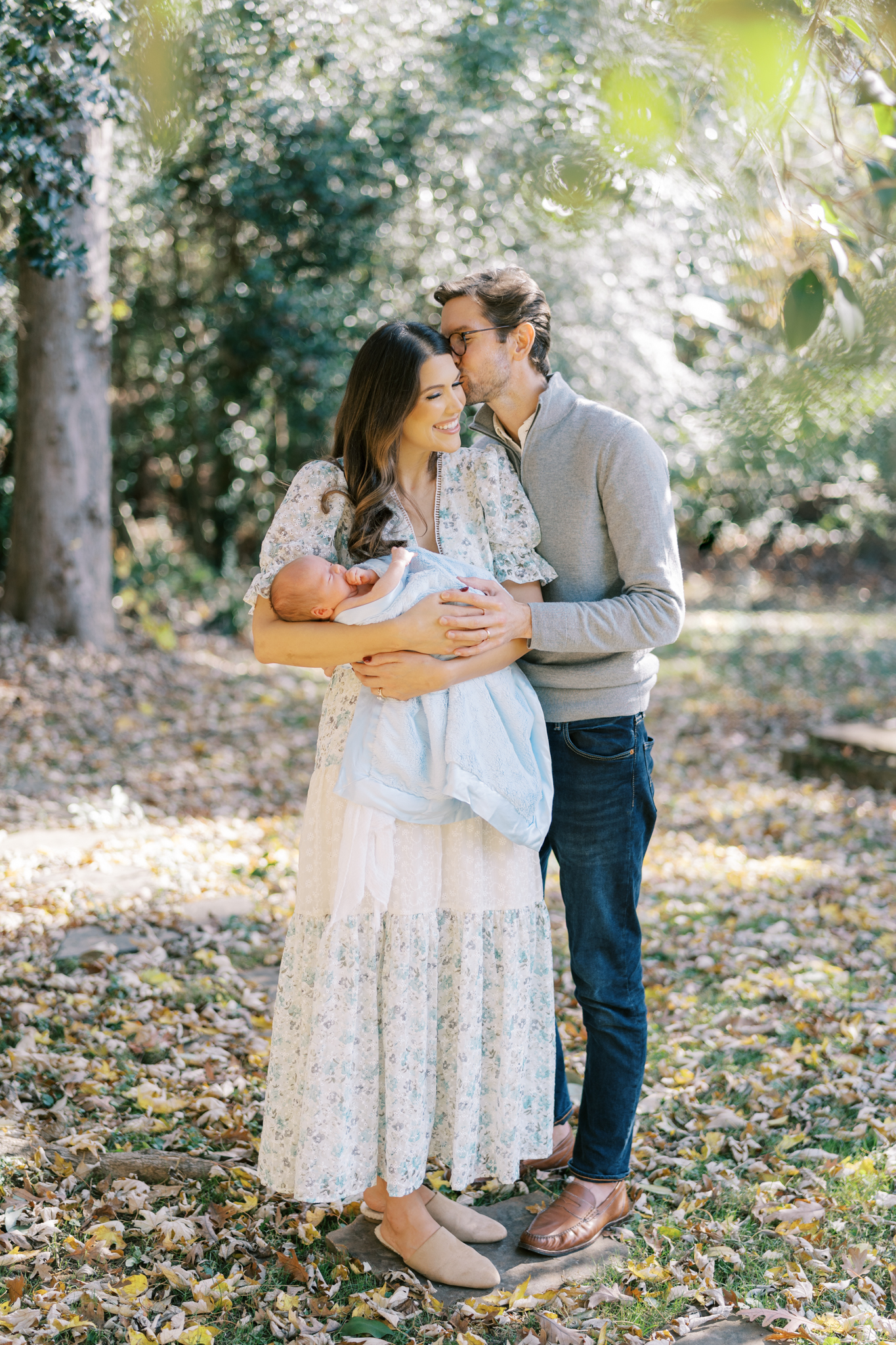 Husband kissing his wife in their Atlanta backyard with their newborn baby boy.