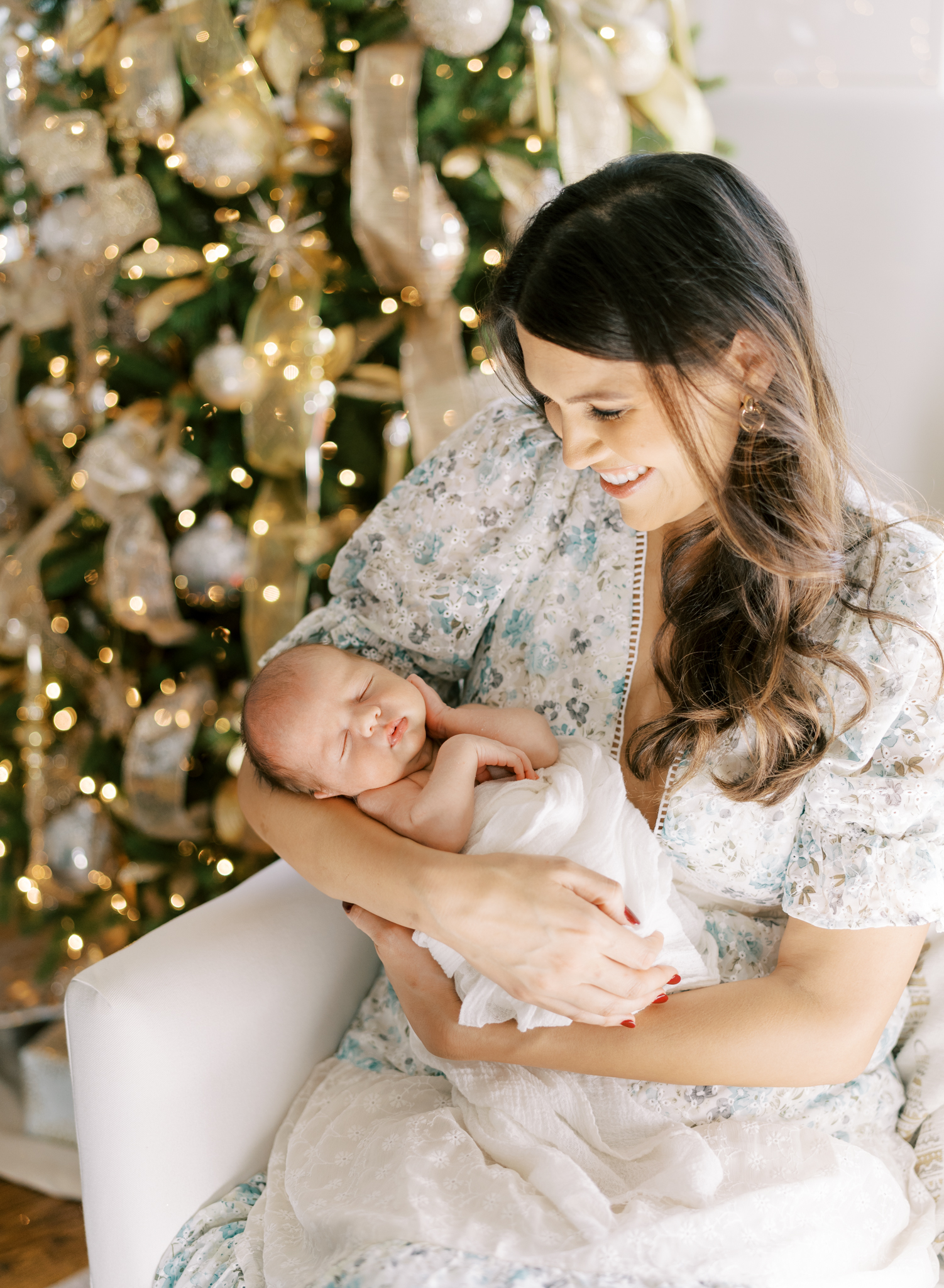 New mom adoring her baby boy in front of the lit Christmas tree. 