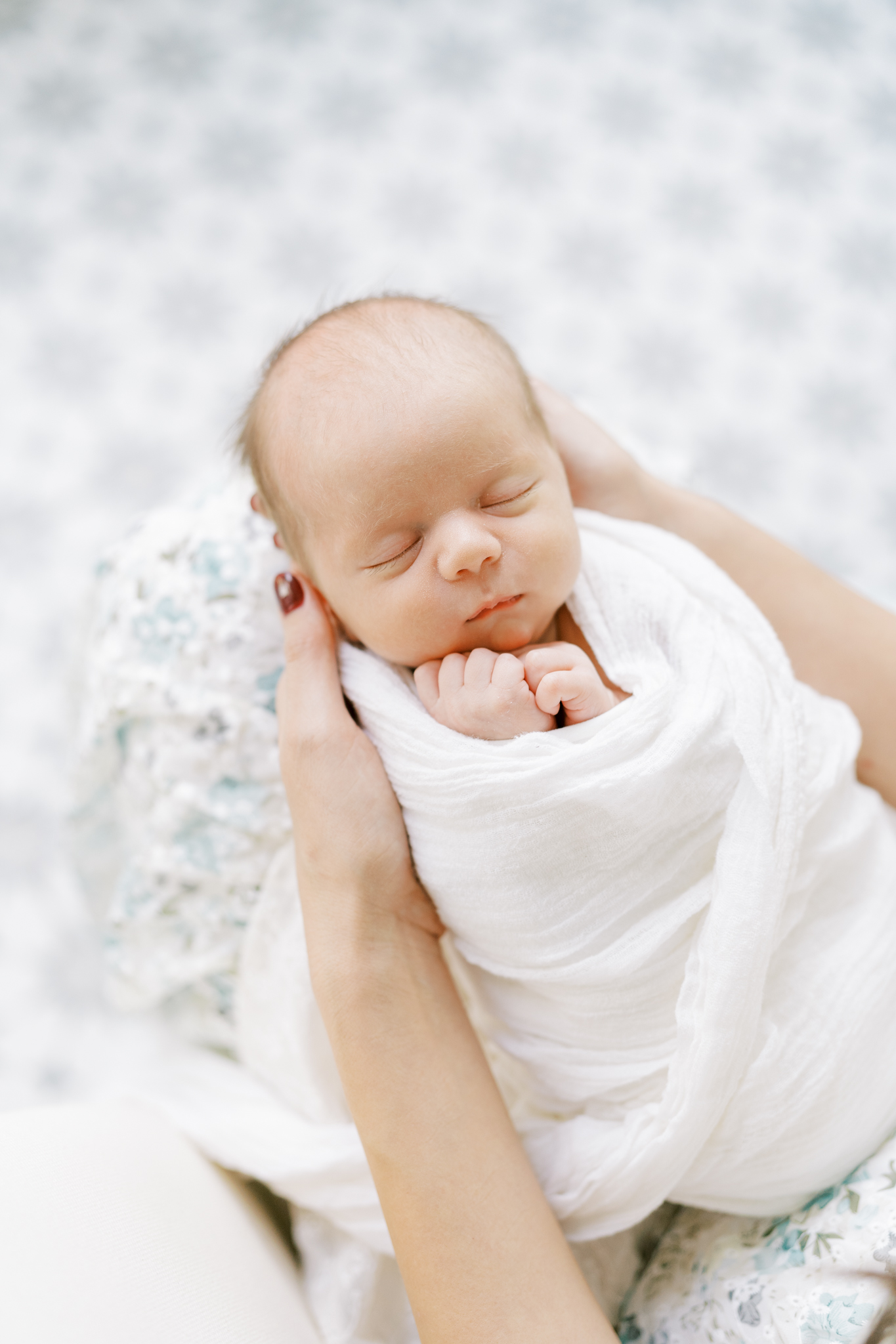 Perfect baby boy swaddled up and being held in moms hands.