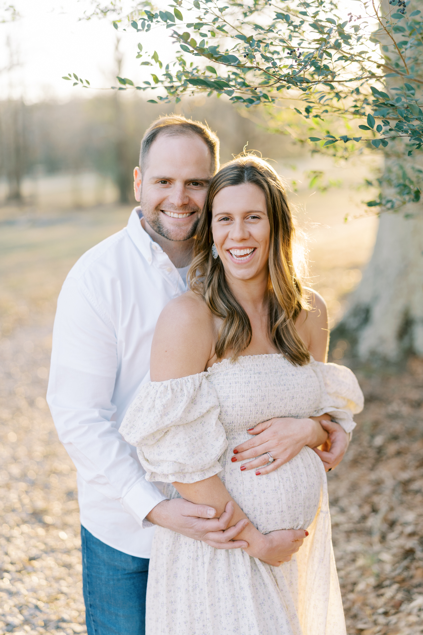 Happy expectant couple embracing and smiling in photo shoot in Cumming, GA