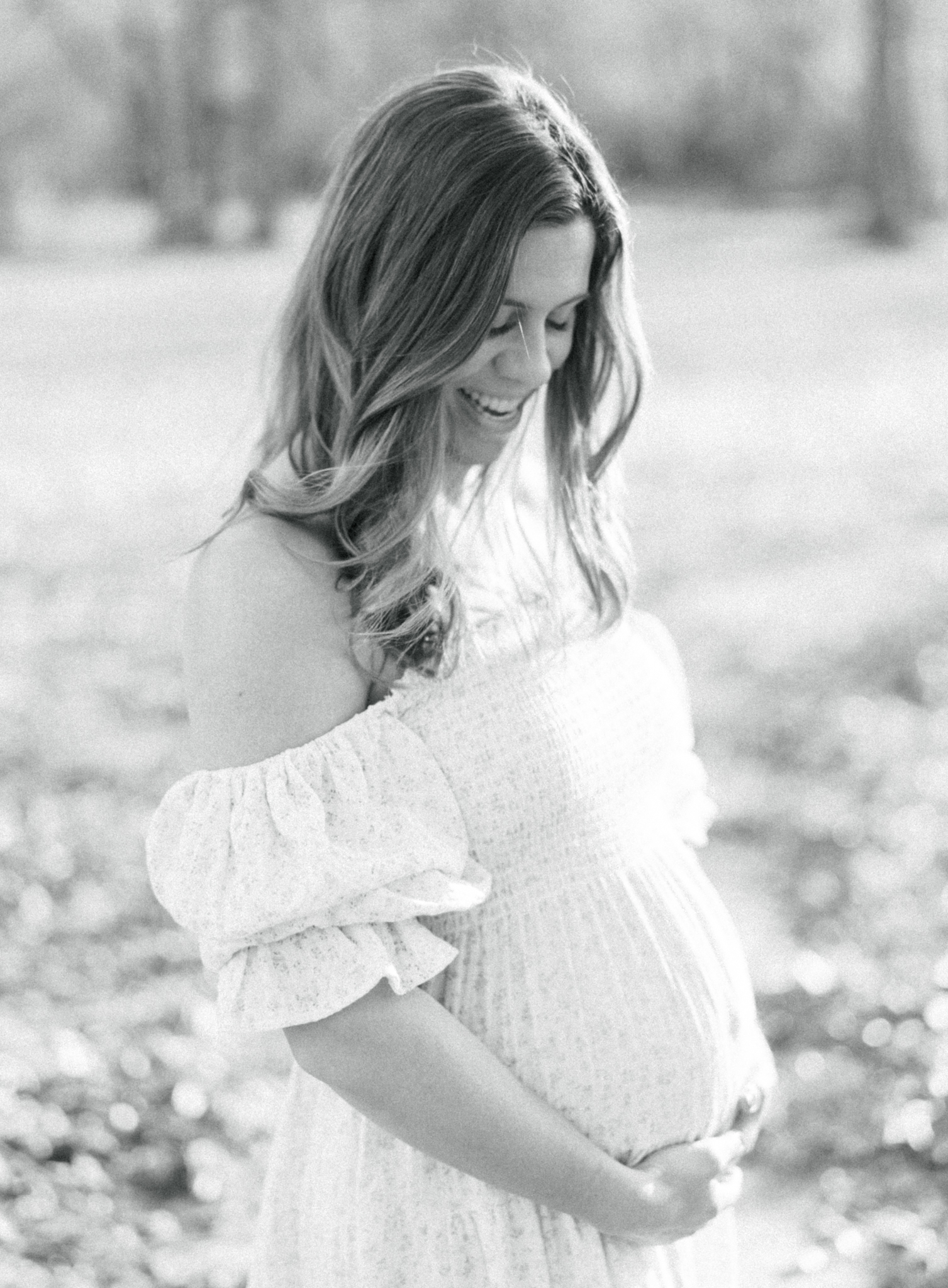 pregnant woman smiling down at her belly in Cumming, GA photo shoot