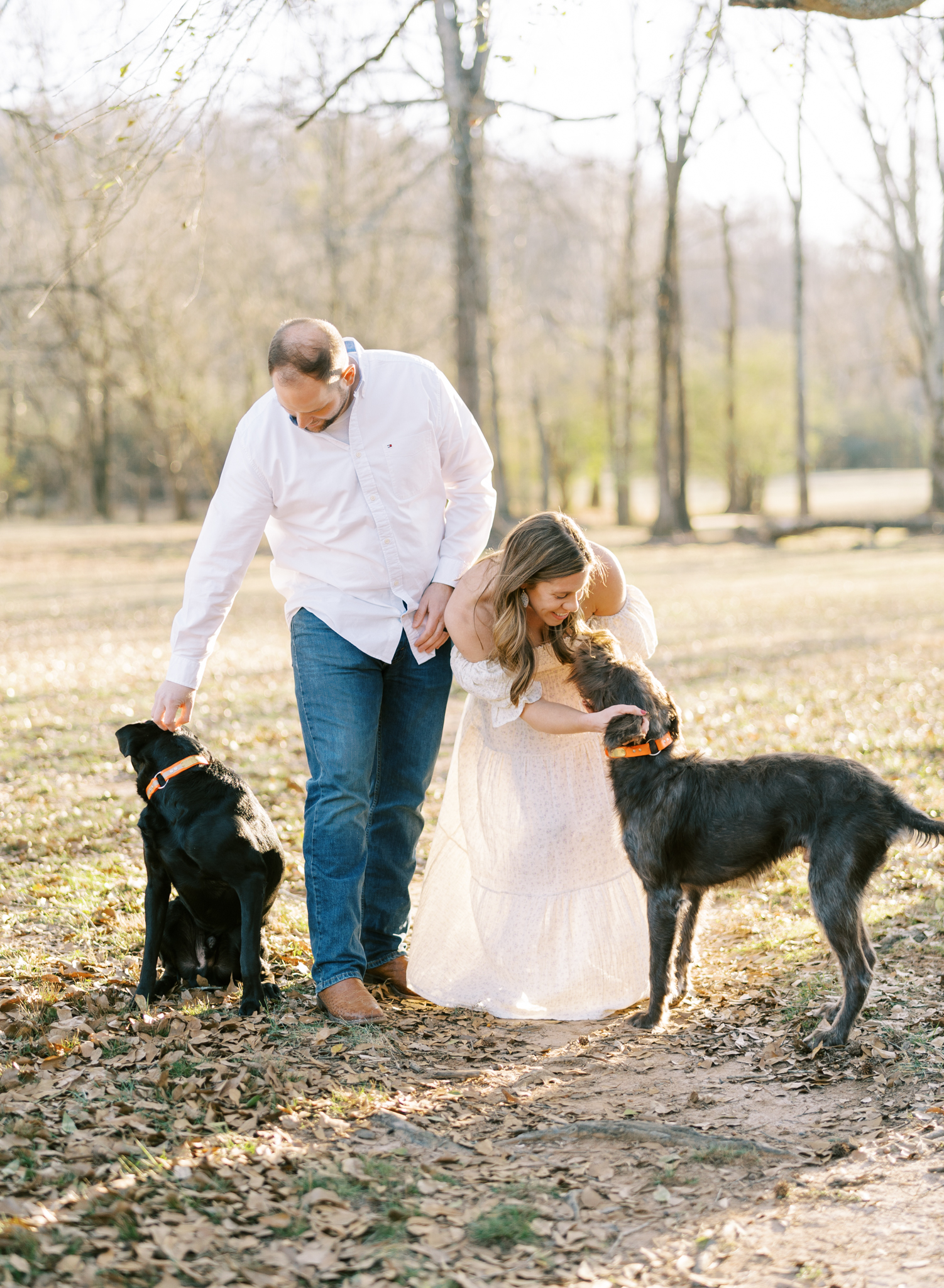 Happy expectant couple playing with their dogs during maternity photoshoot in Cumming GA