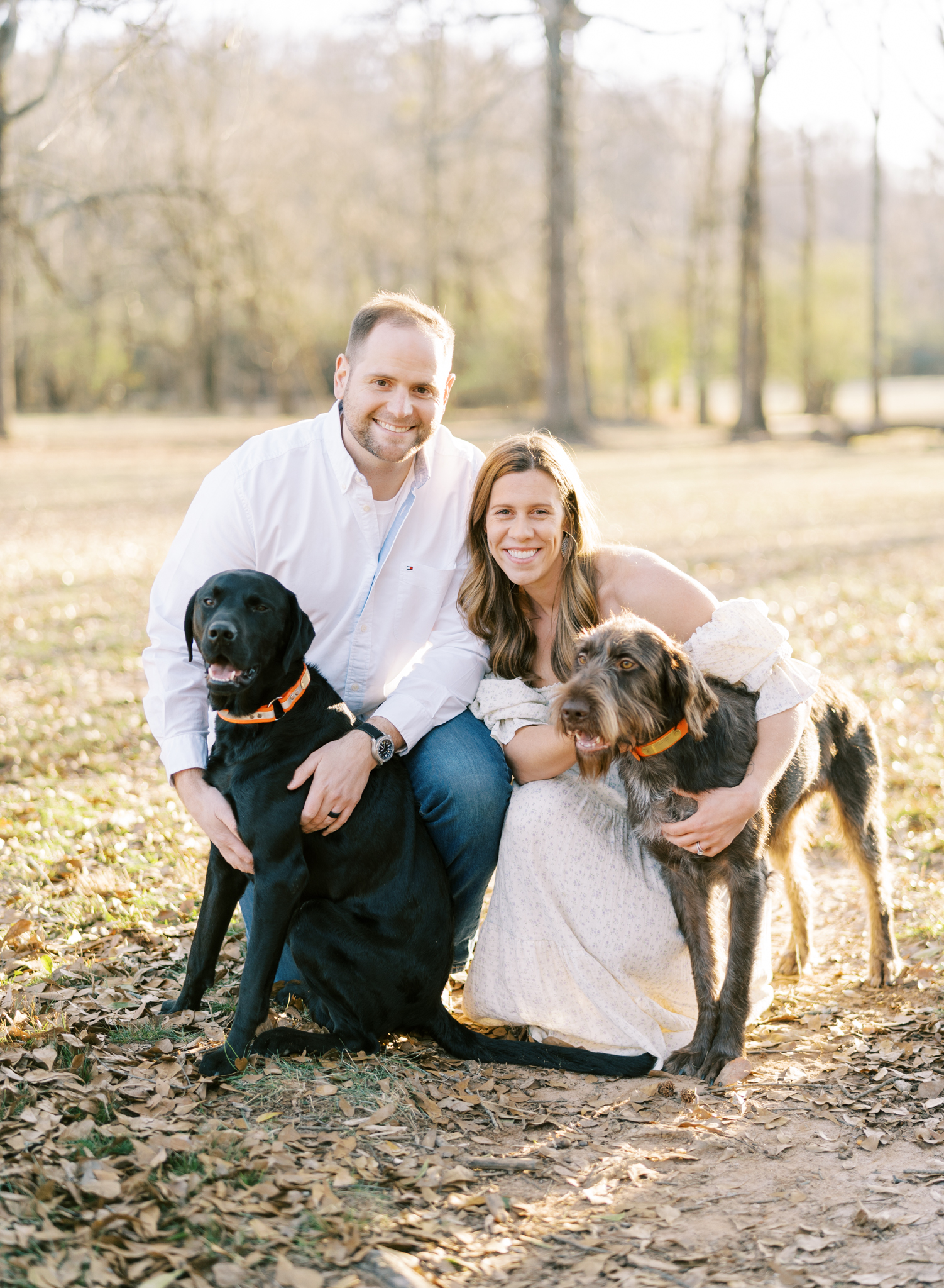 Happy expectant couple playing with their dogs during maternity photoshoot in Cumming GA