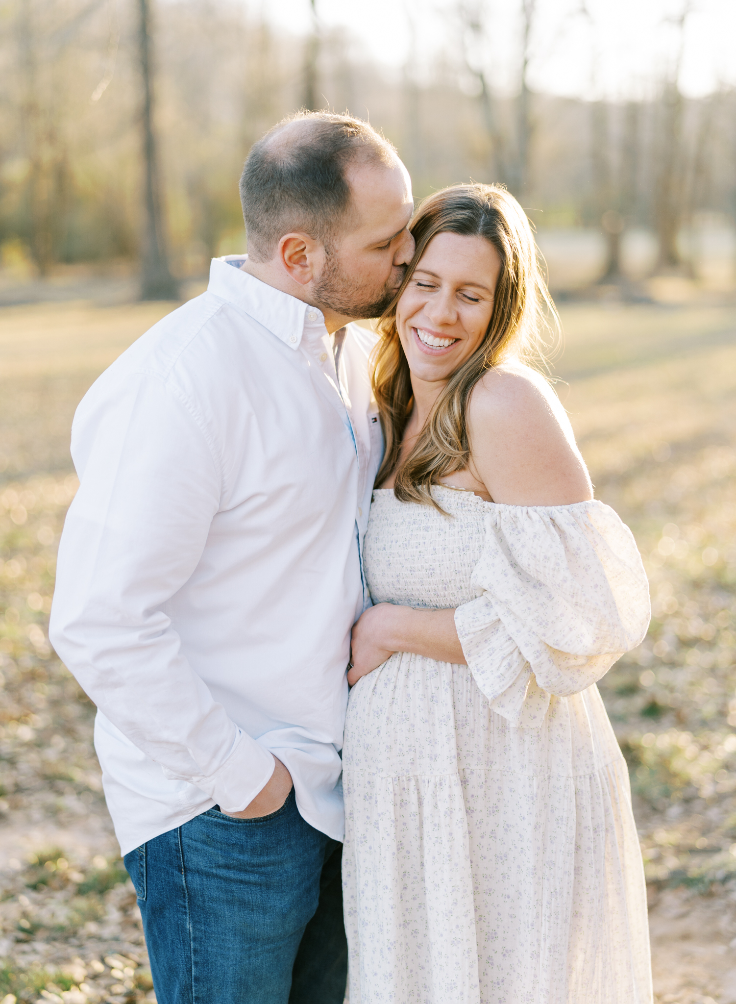 Husband kissing adorable expectant wife on the side of the cheek in winter photoshoot
