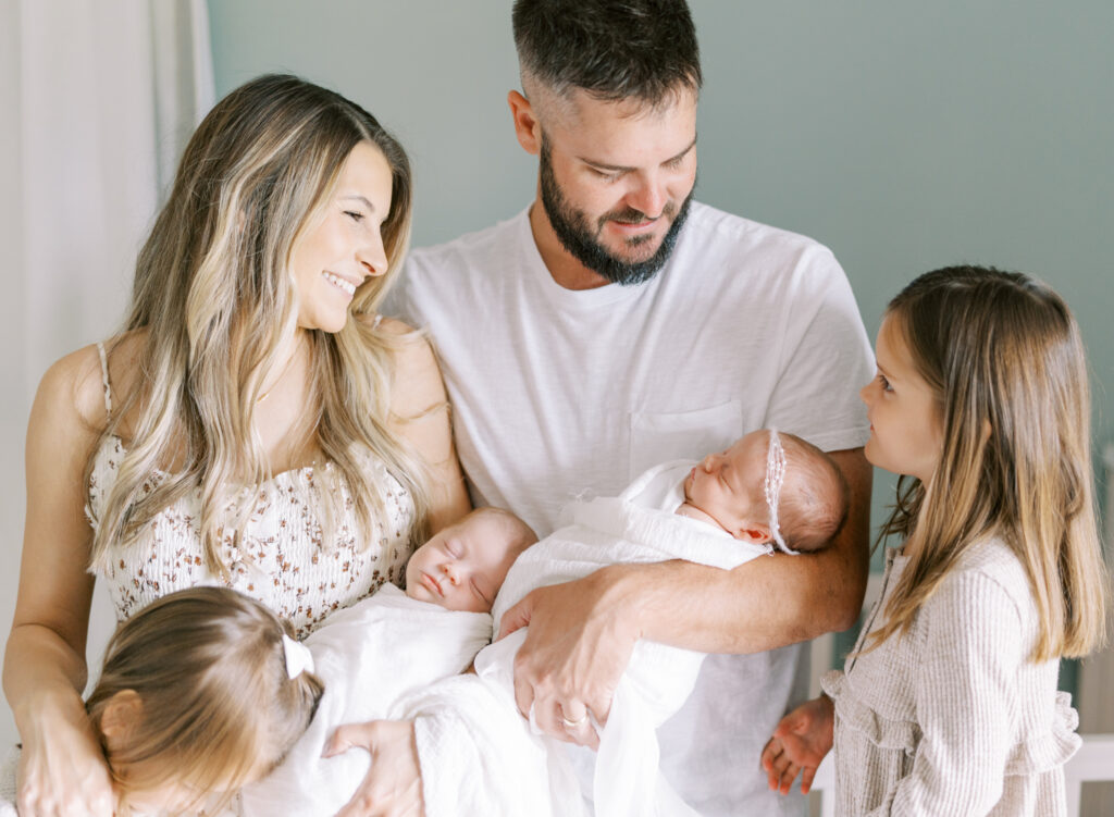 family interacting while holding newborn twins