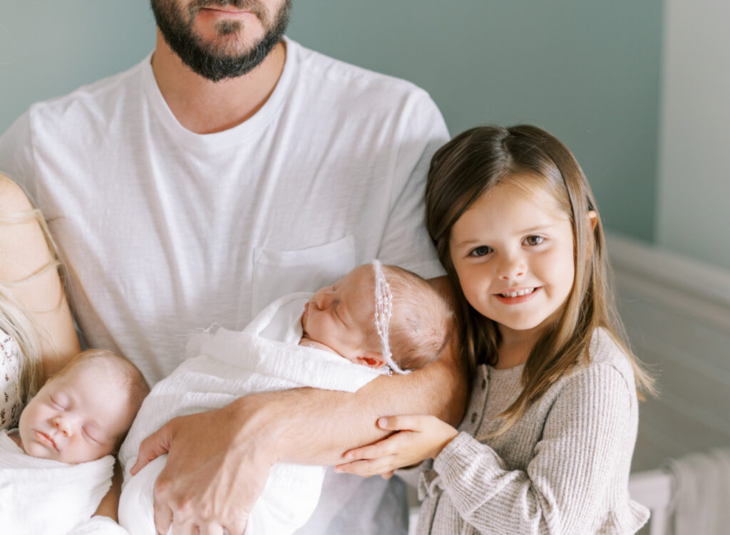 Big sister posing next to her newborn baby brother and sister twins