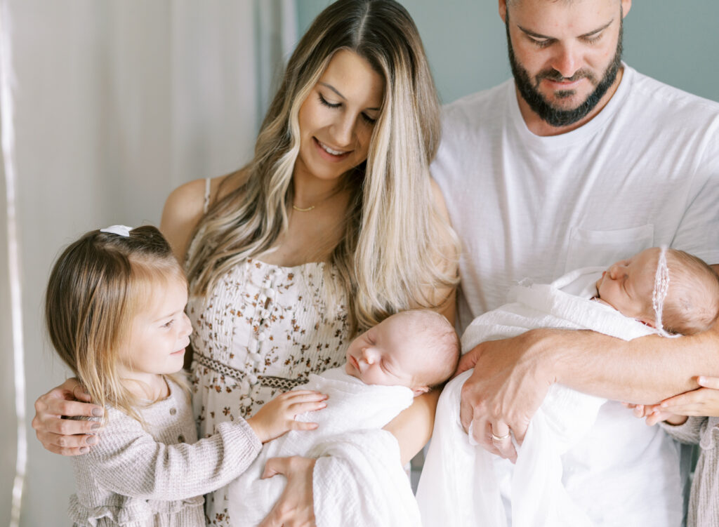 Parents holding newborn twins and toddler