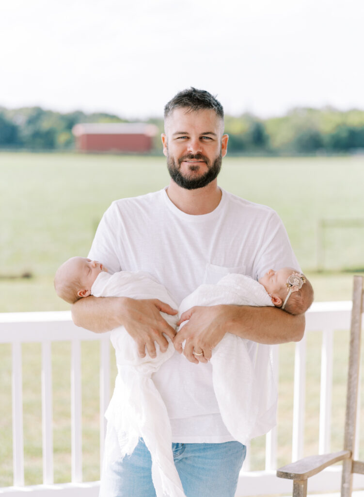 Proud dad holding newborn twins on front porch in North GA