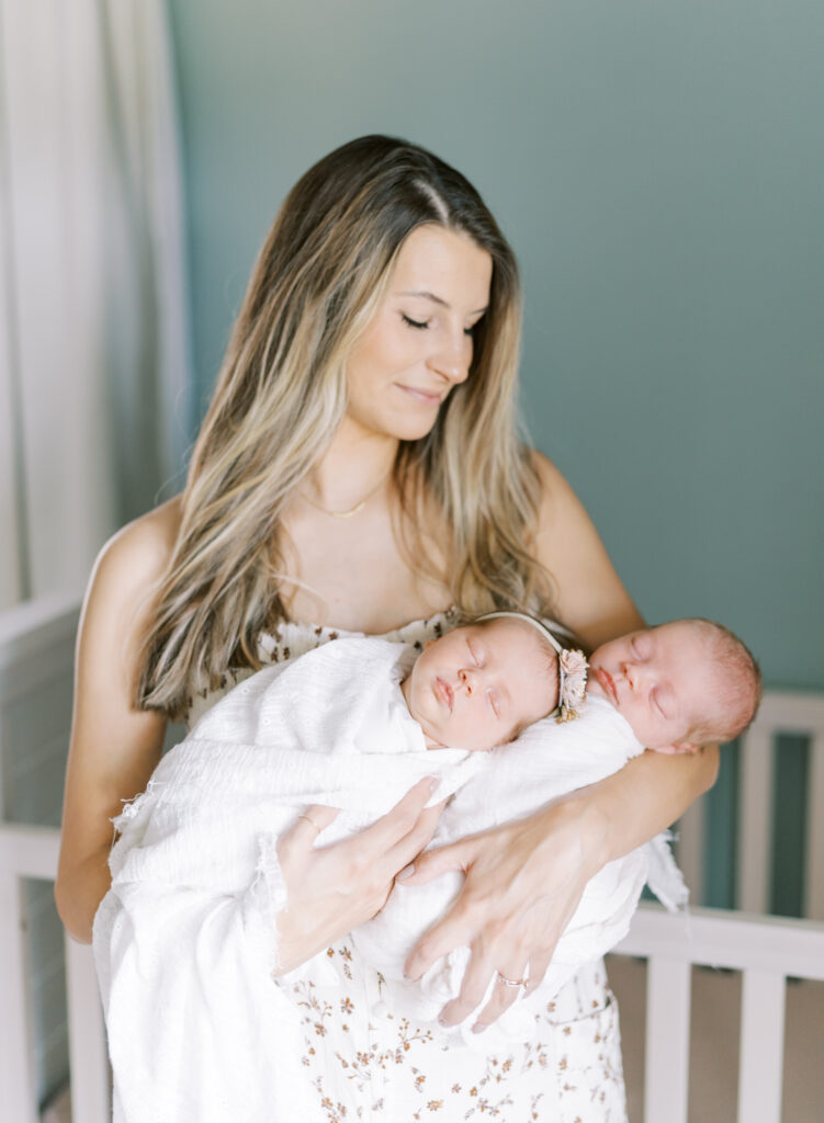 Beautiful mother holding two newborn babies in her arms