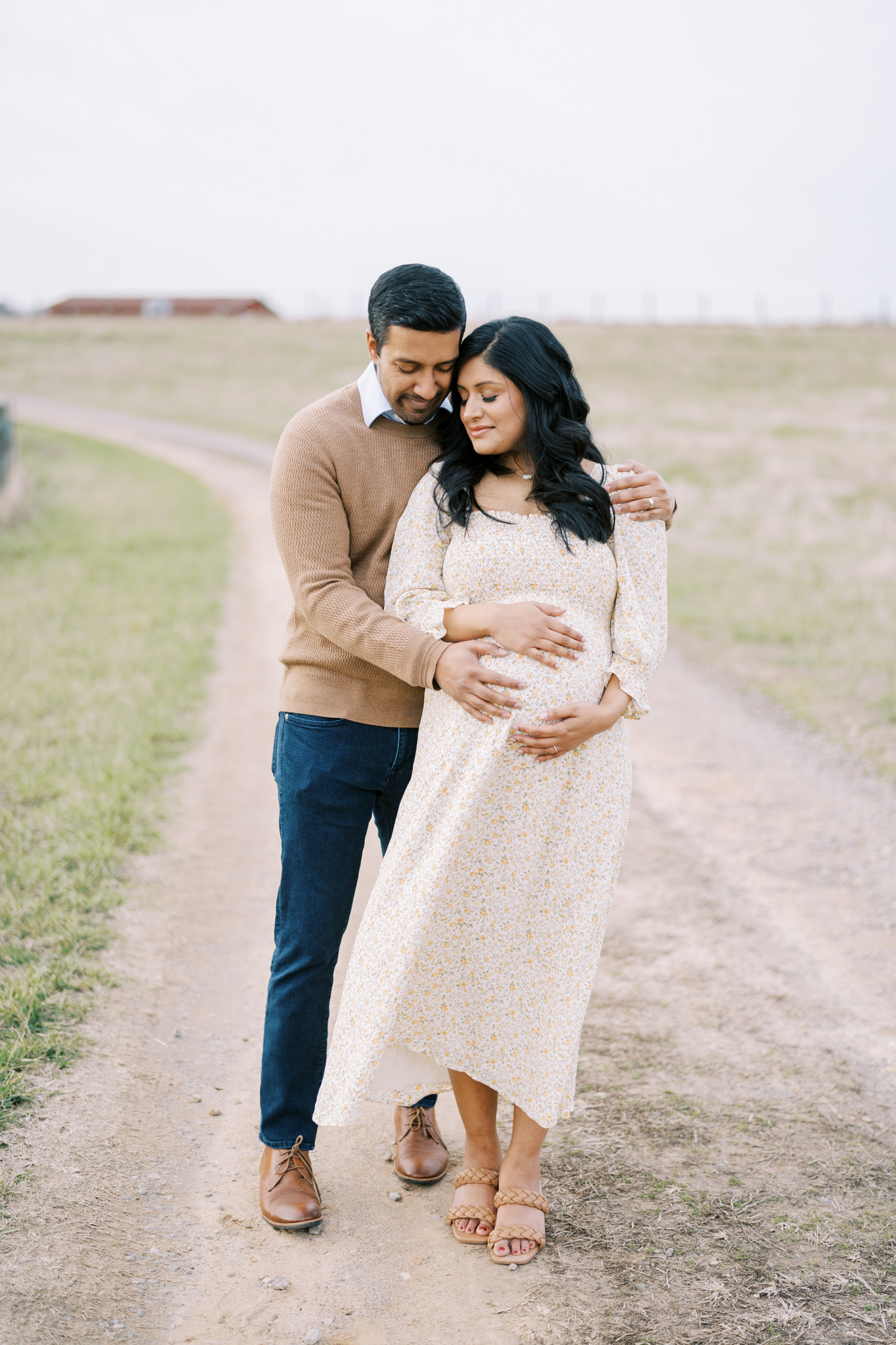 expecting parents holding each other on a country road