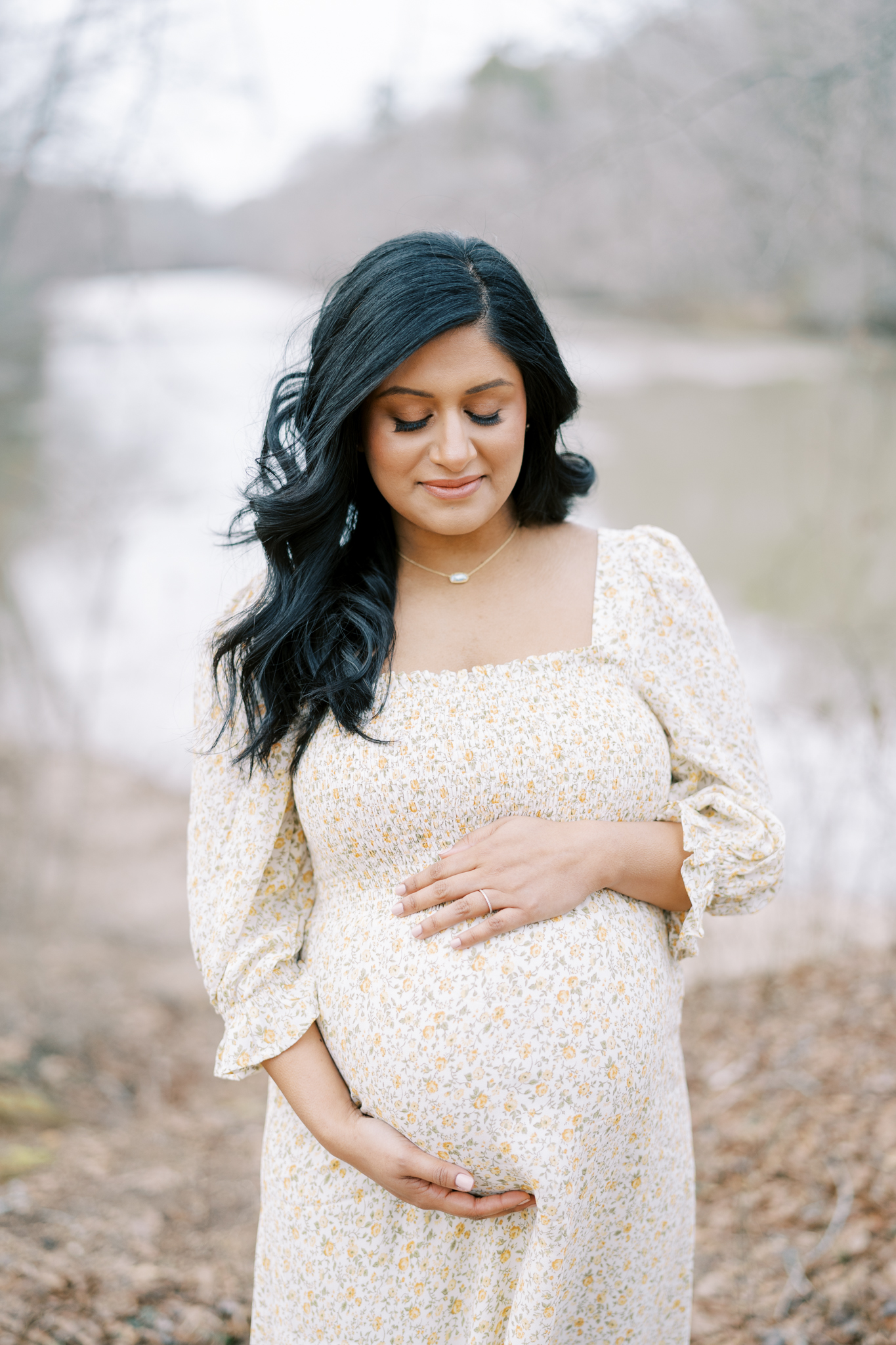 pregnant mom closing eyes in front of river