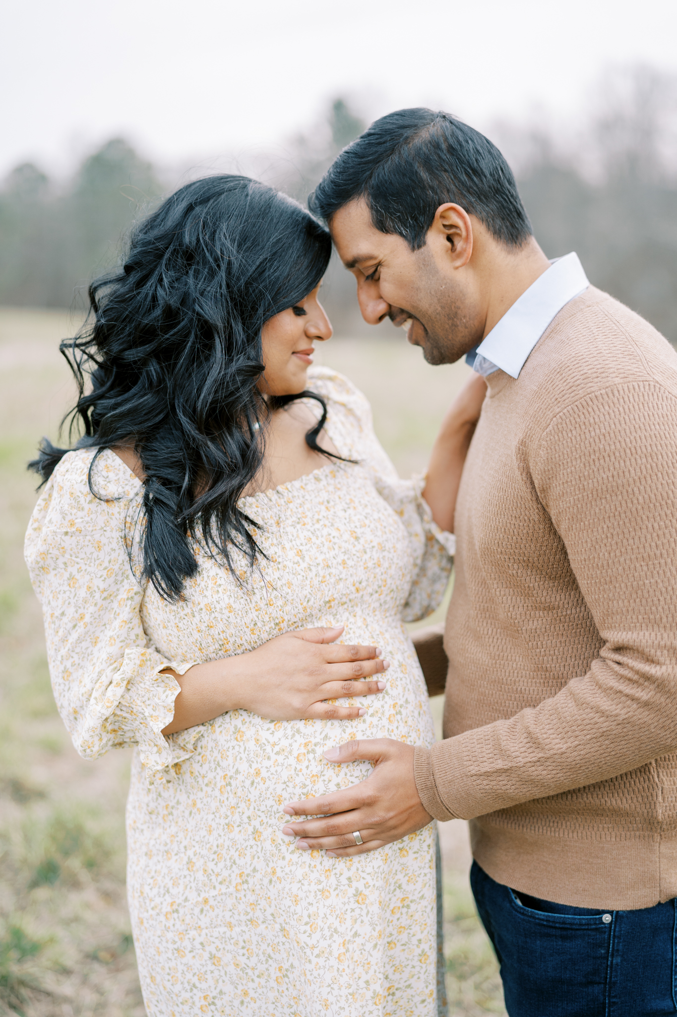 husband and wife smiling down at each other for natural maternity photos