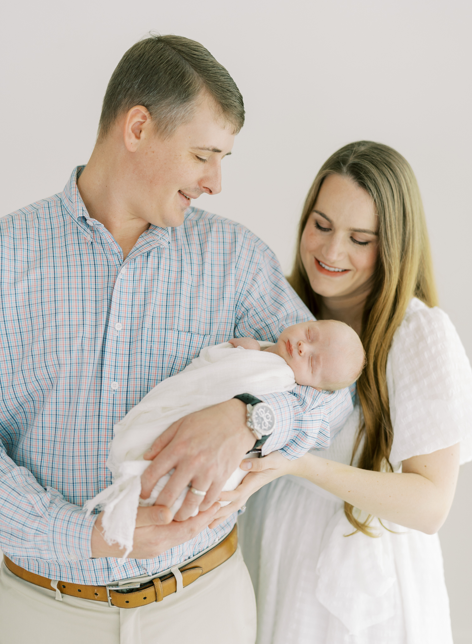 mom and dad smiling at newborn son during studio newborn session in Cumming, GA