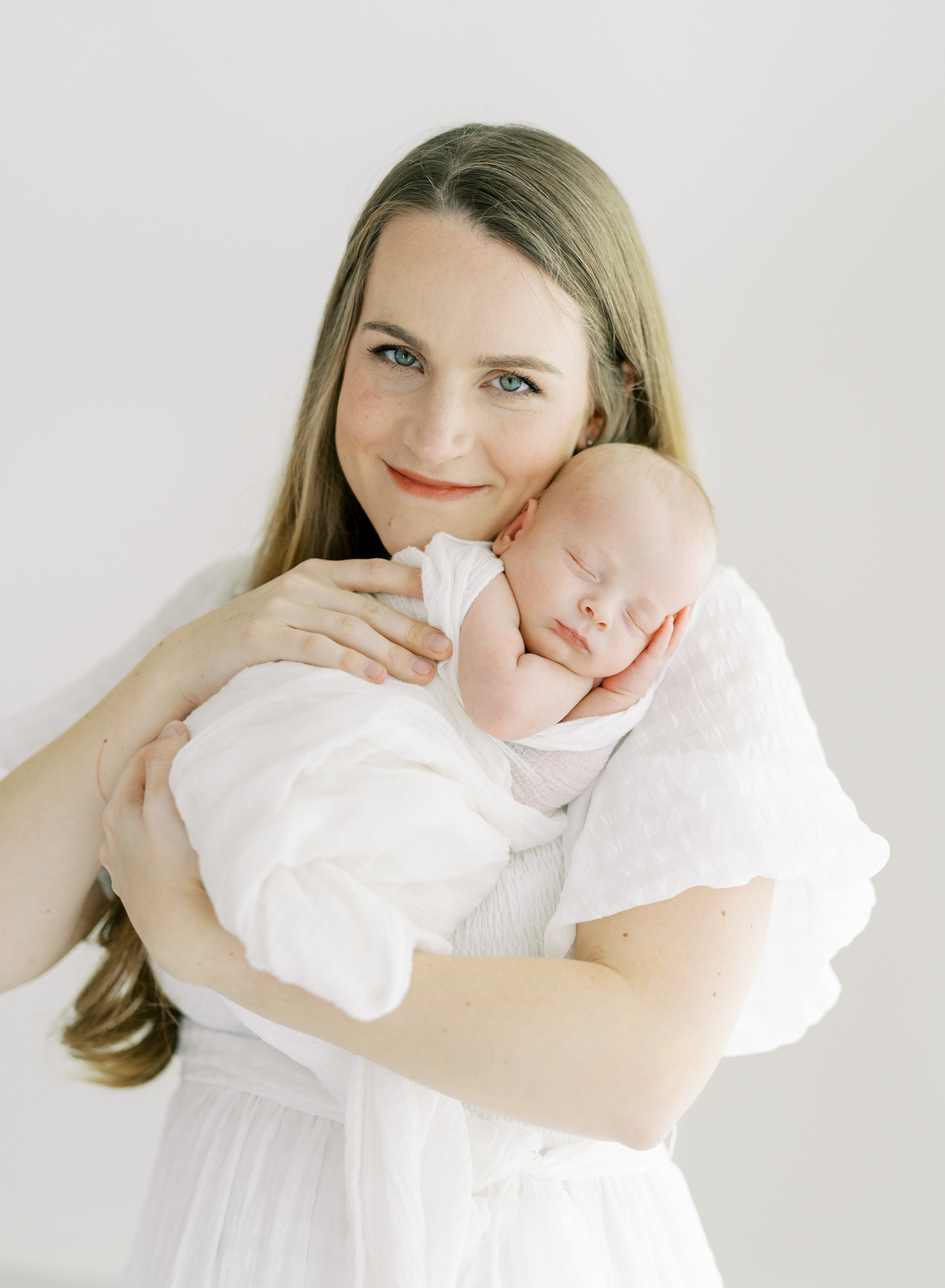 glowing new mom holding baby boy on chest in studio newborn photos in Atlanta