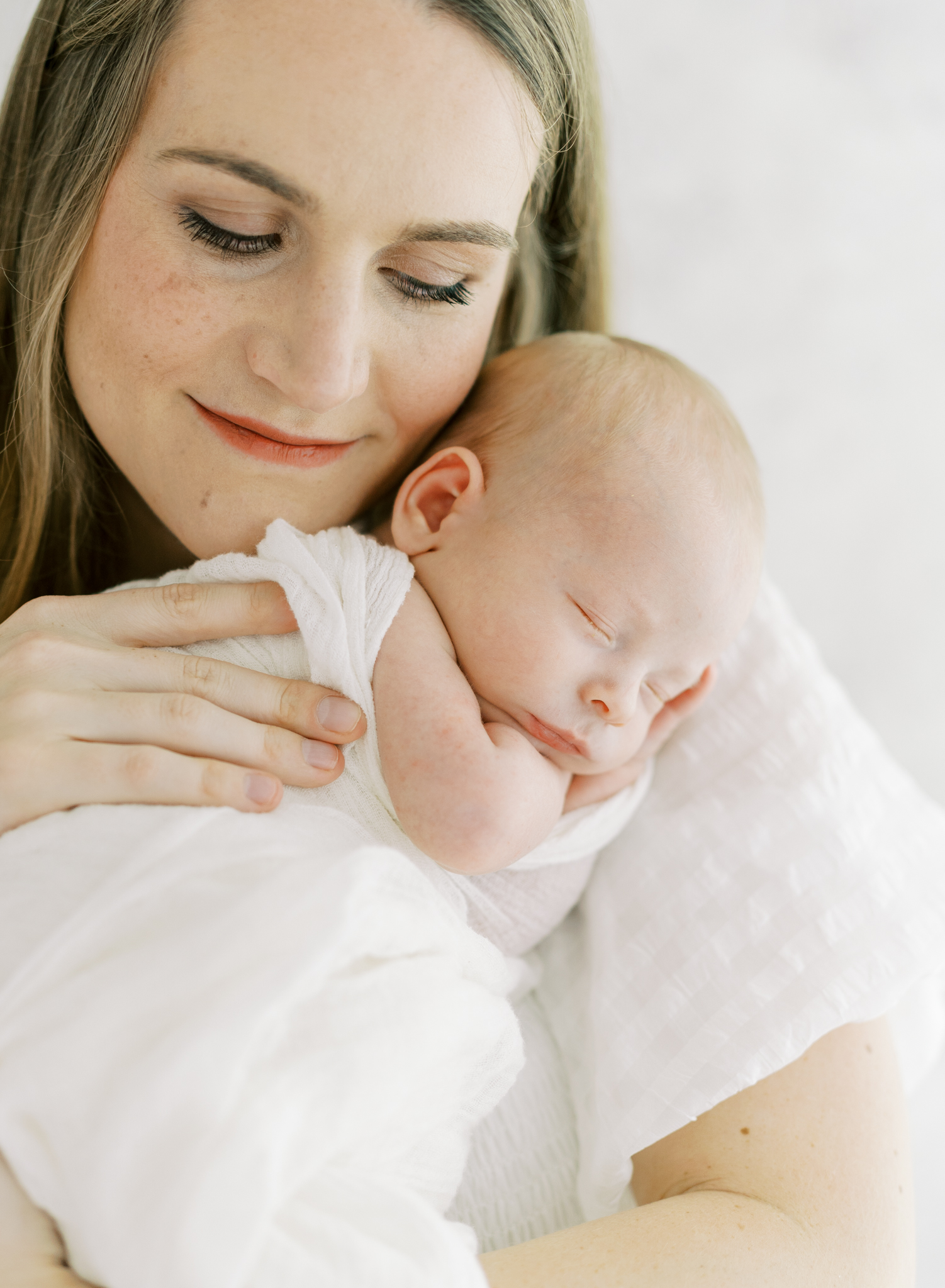 glowing new mom holding baby boy on chest in studio newborn photos in Atlanta