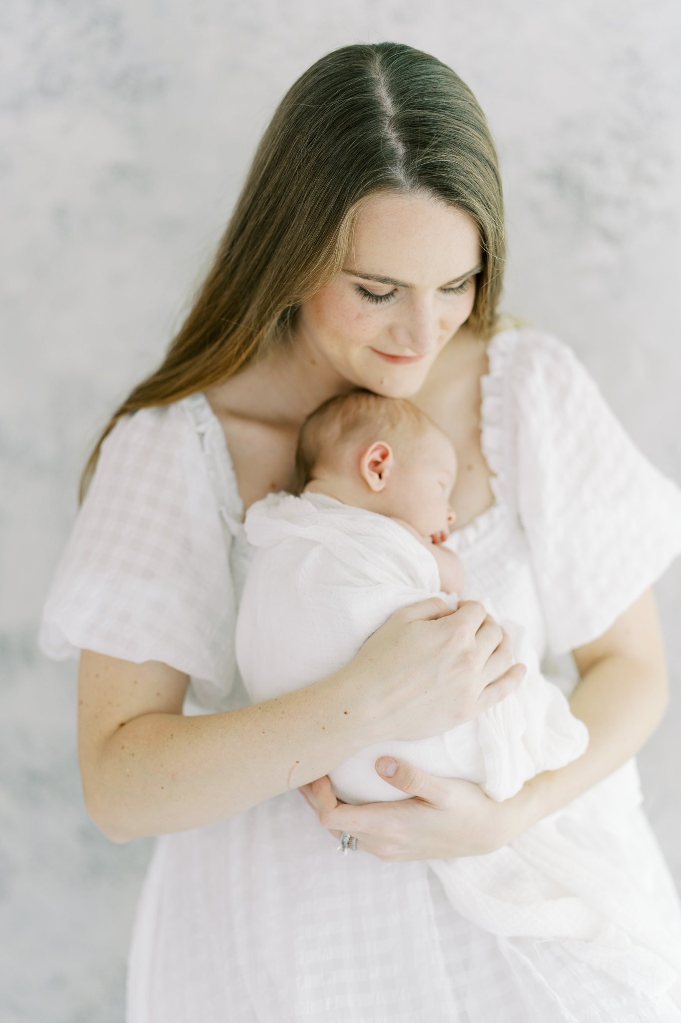 glowing new mom holding baby boy on chest in studio newborn photos in Atlanta