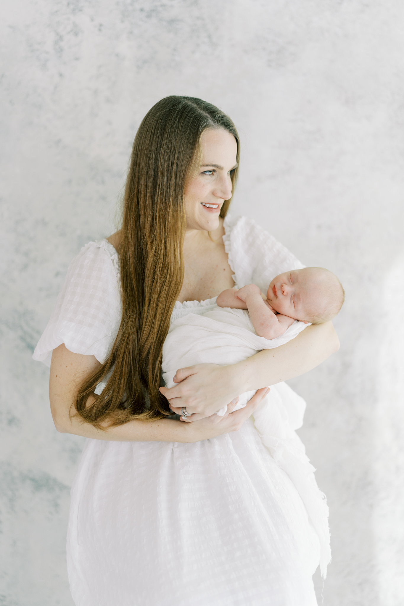 glowing new mom holding baby with painted backdrop in studio newborn photos in Atlanta