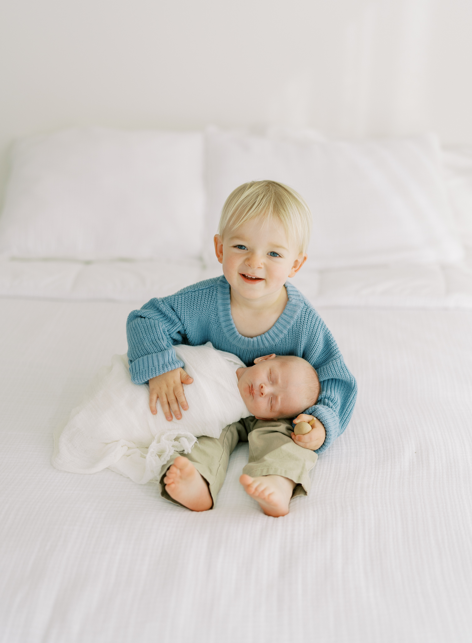 toddler holding newborn brother in cumming, ga photography studio